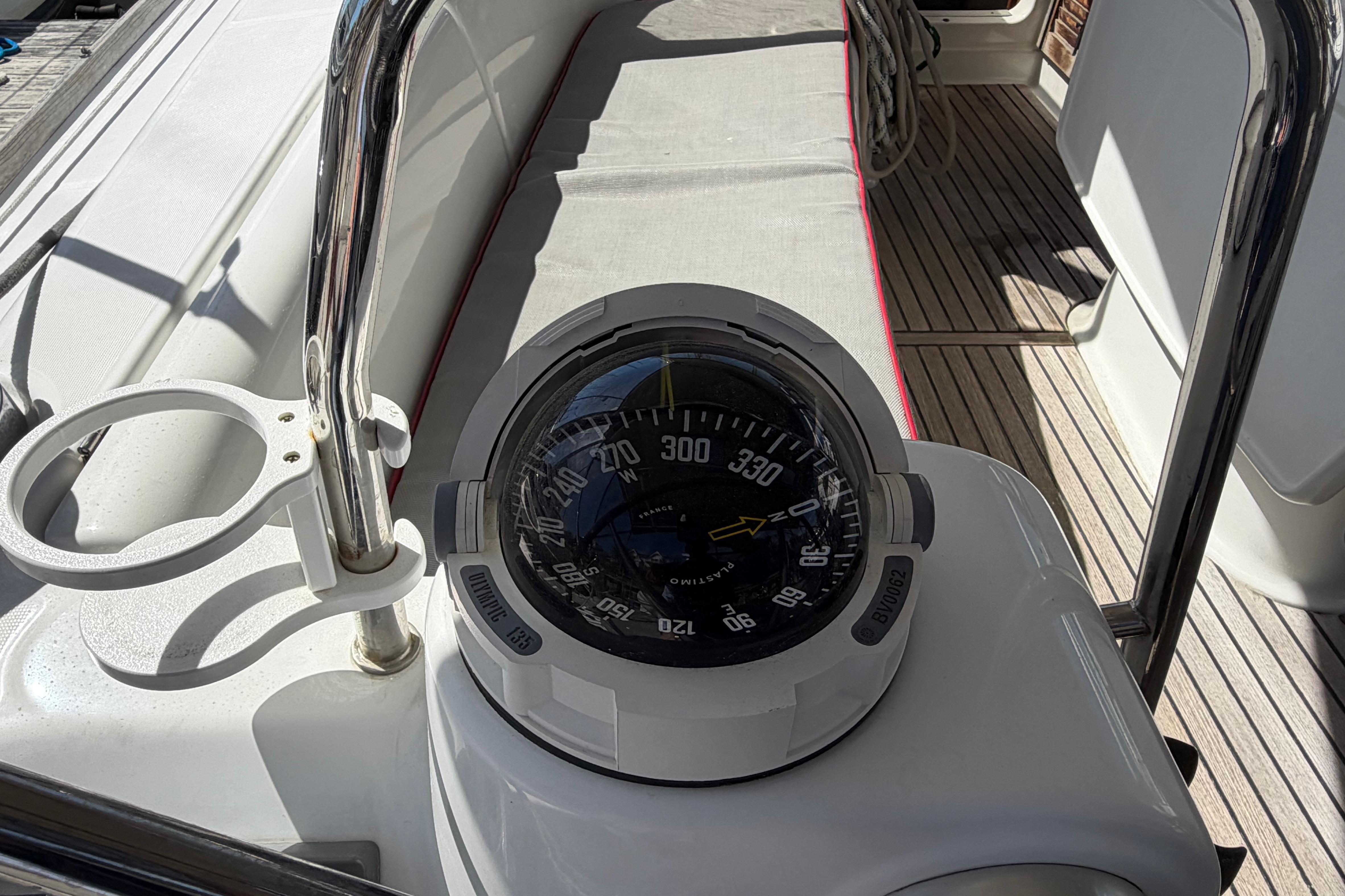 Compass on deck of 2008 Beneteau 43 sailboat, with teak flooring and stainless steel railing.