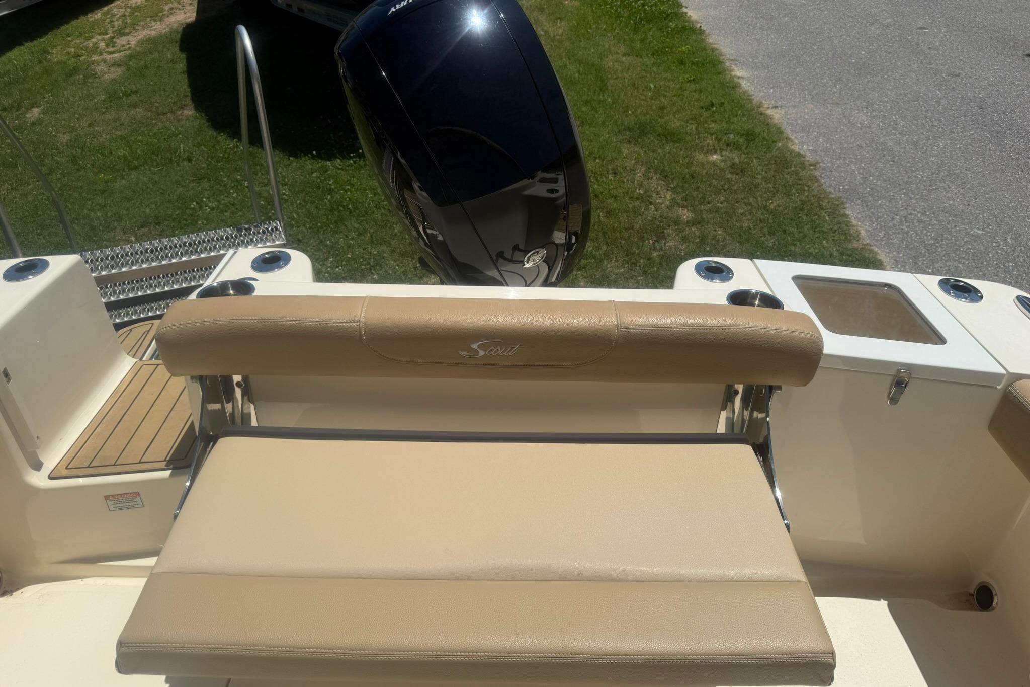 2021 Scout 215 Dorado boat interior with seating and motor, parked on grass.