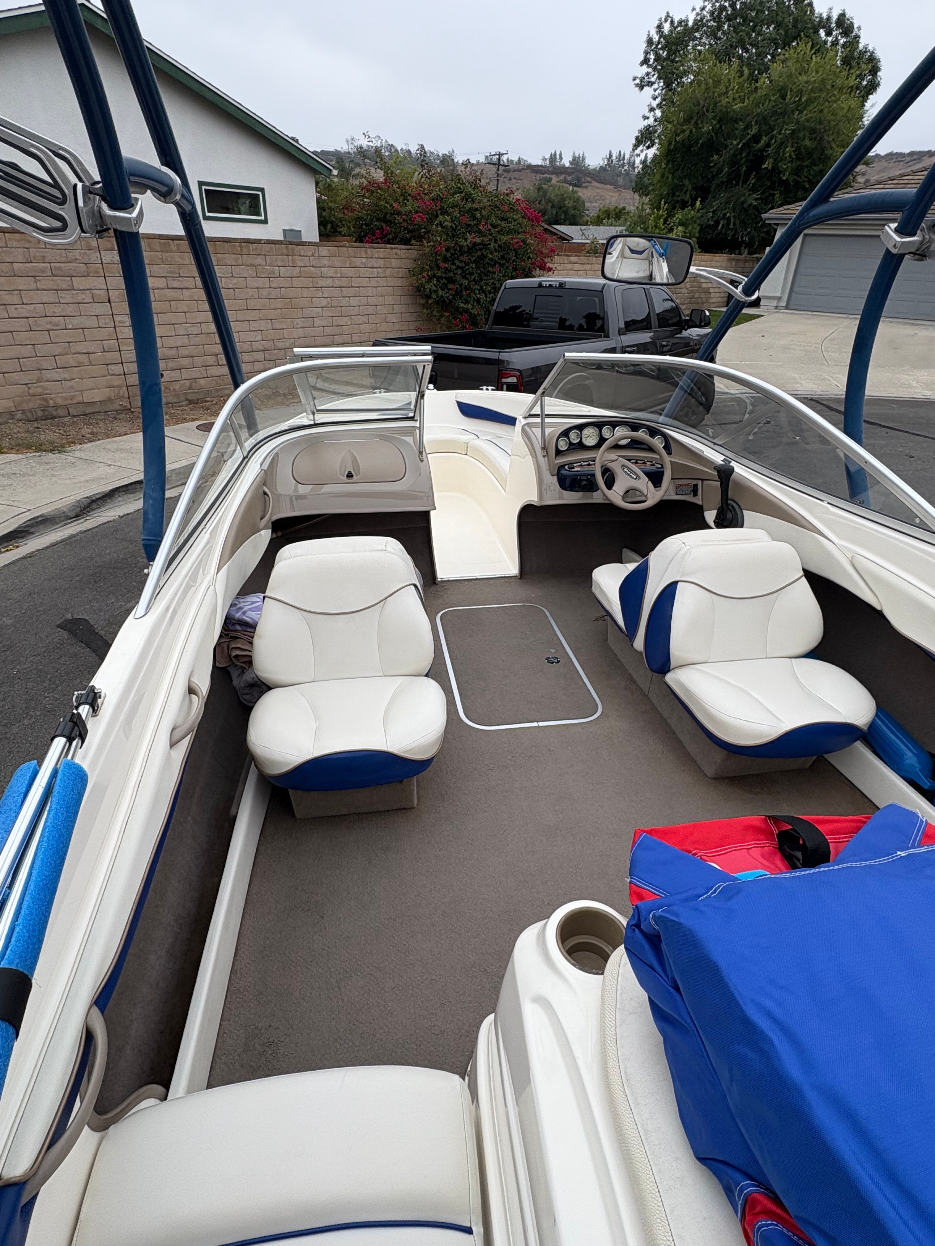 2003 Bayliner CAPRI 205 boat interior with white and blue seating, parked outdoors.