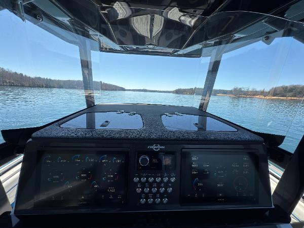 2024 Fountain 34 SC boat dashboard with digital controls, overlooking a serene lake view.