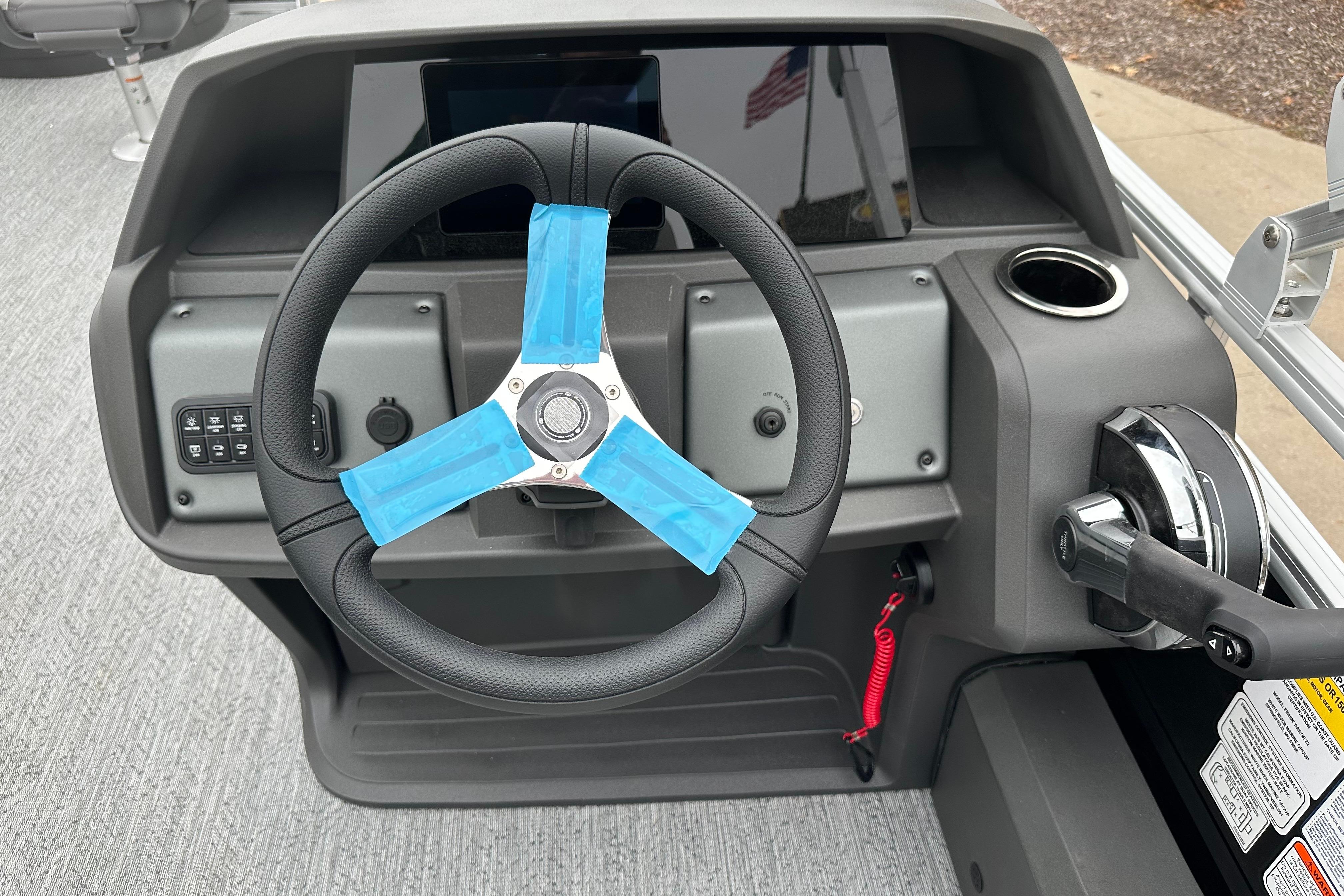 Steering console of 2026 Sun Tracker Fishin' Barge 22 DLX with blue-taped wheel.