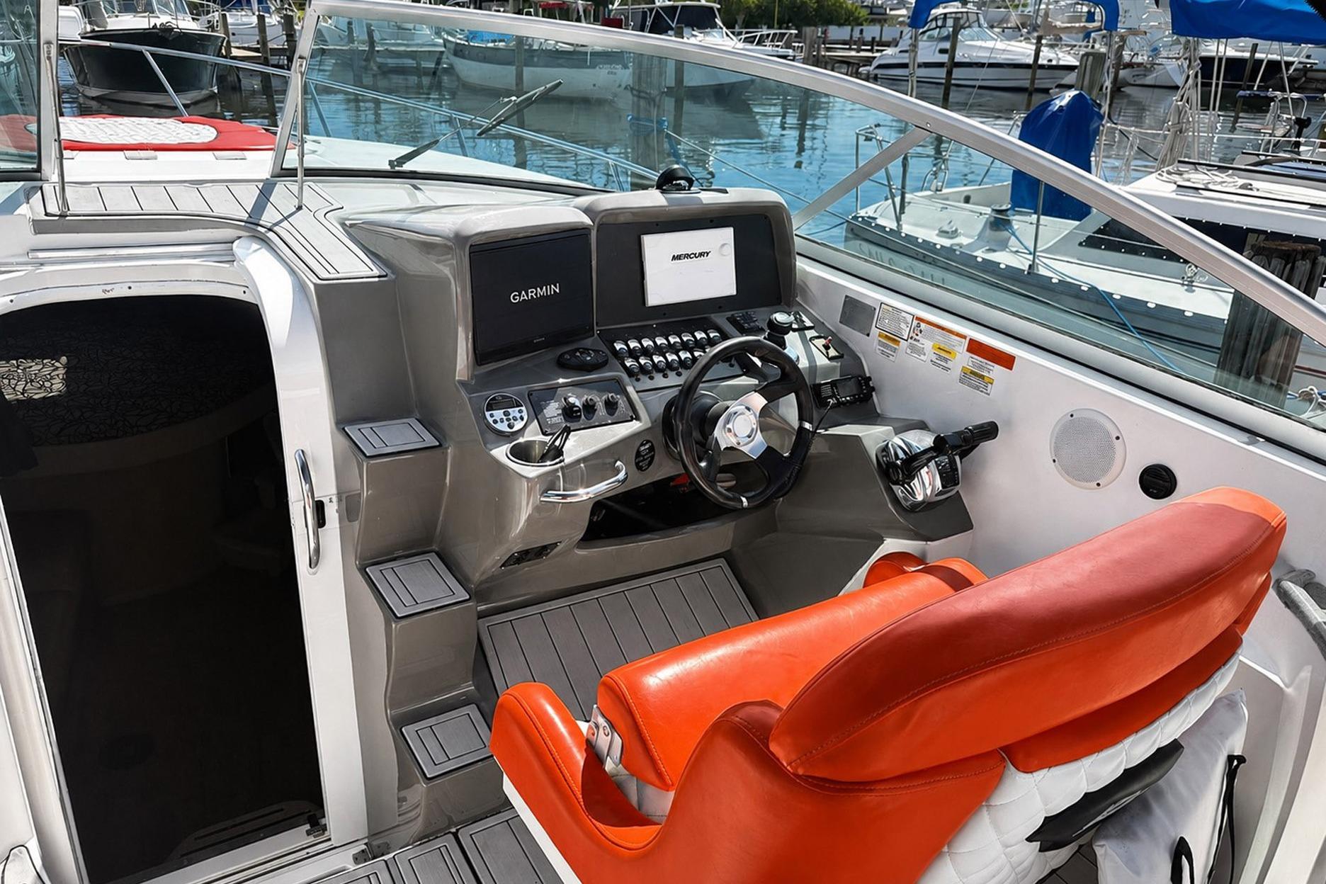2012 Rinker 310 Express Cruiser LE helm with Garmin navigation and vibrant orange seating.