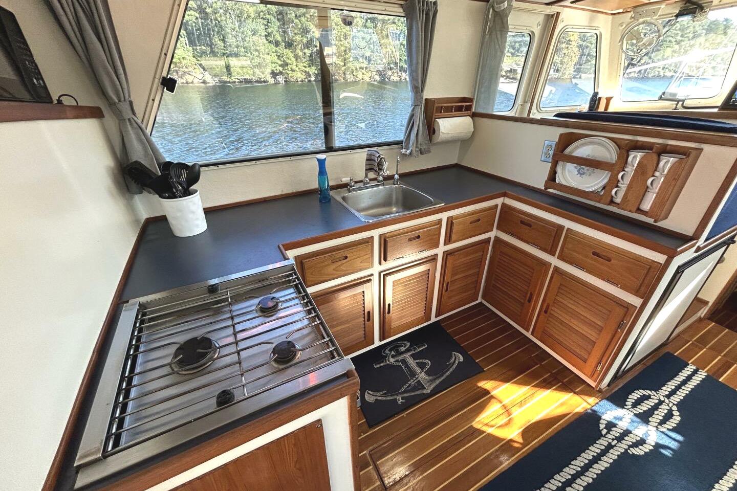 Interior of a 1997 Rosborough Trawler kitchen with stove, sink, and wooden cabinets.