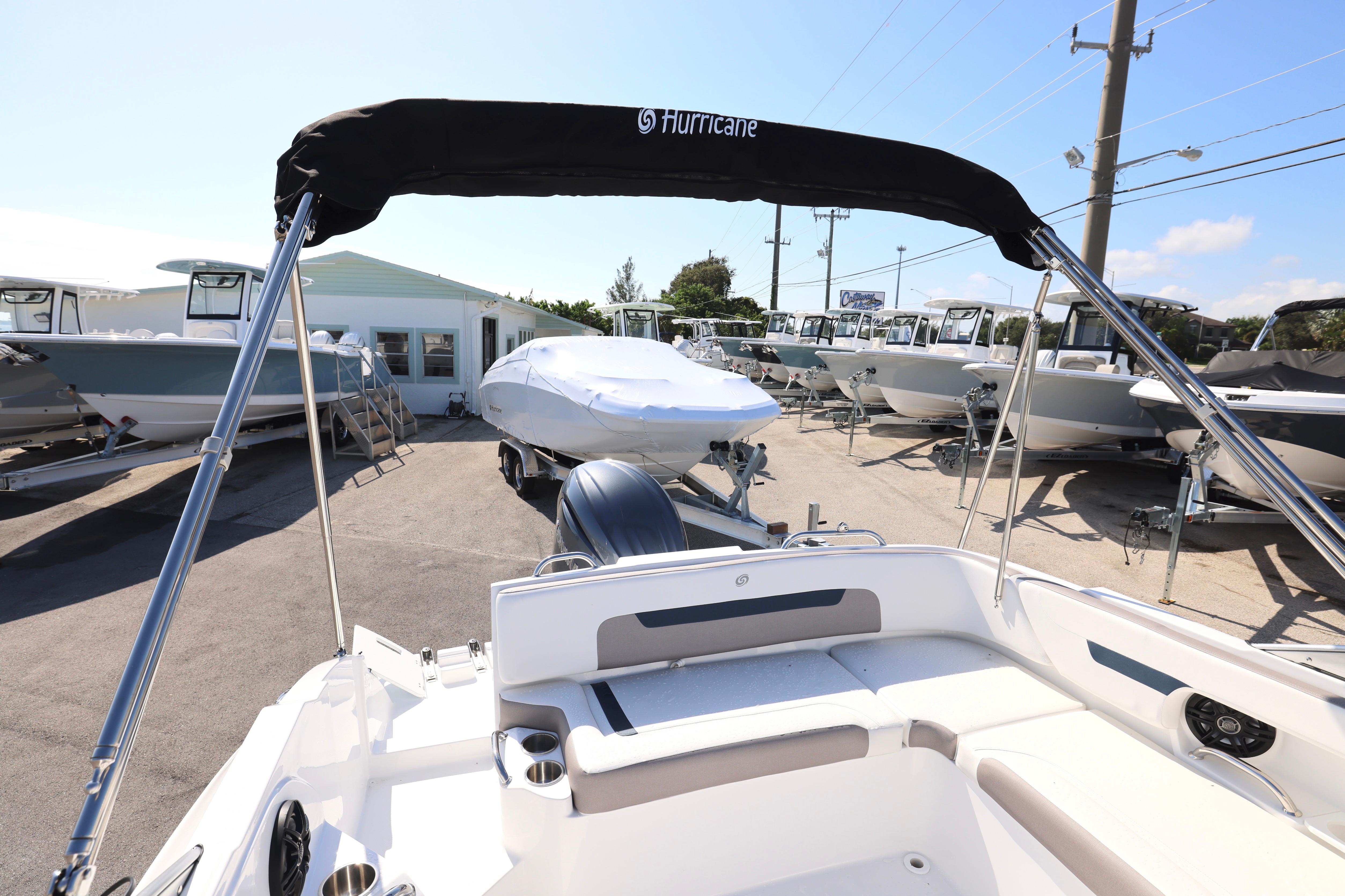 2026 Hurricane SunDeck 235 OB boat at a dealership, surrounded by other boats.