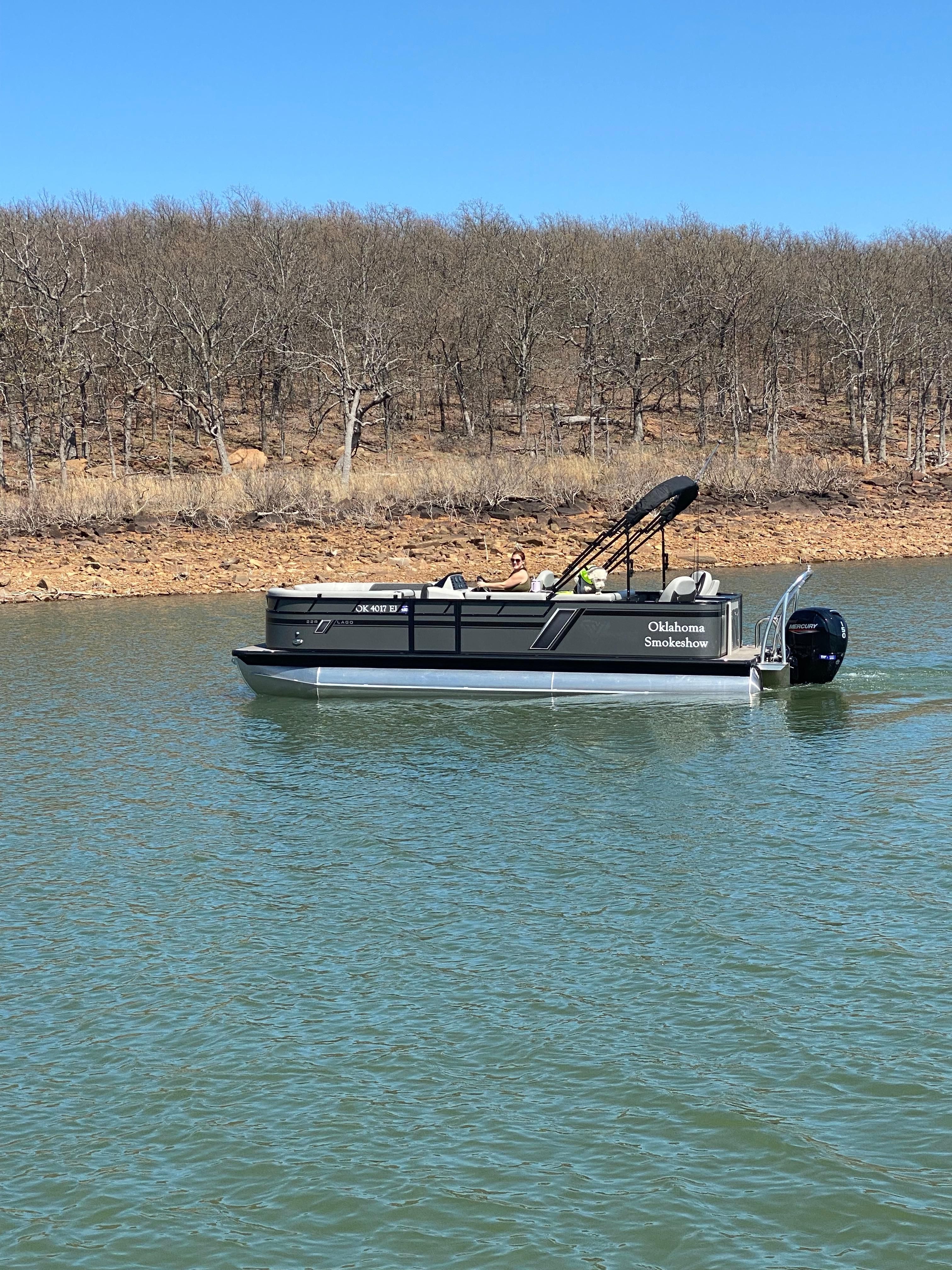 2022 Viaggio Lago boat on a calm lake near a wooded shoreline.