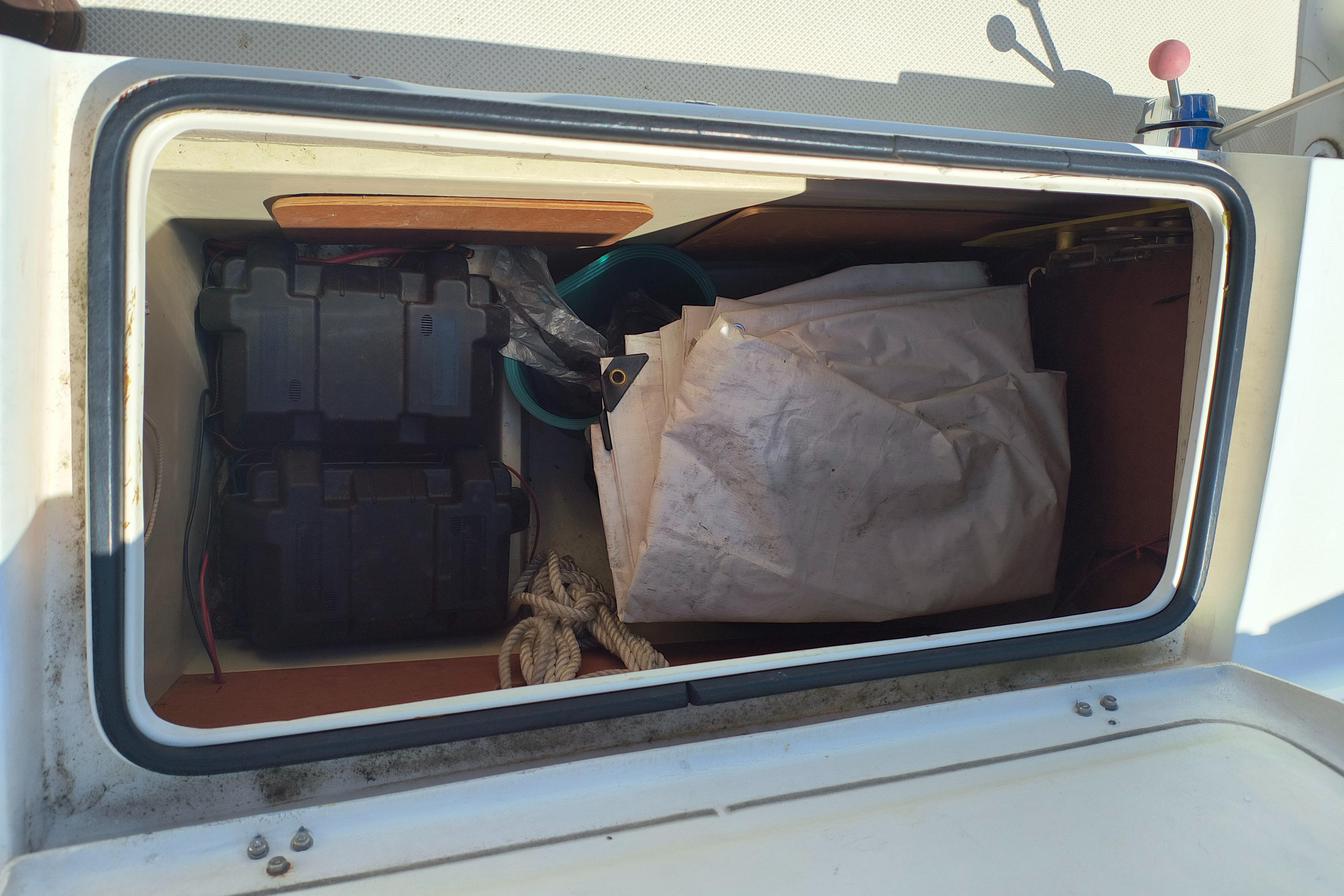 Storage compartment of a 1985 Catalina 27 sailboat with battery and ropes.