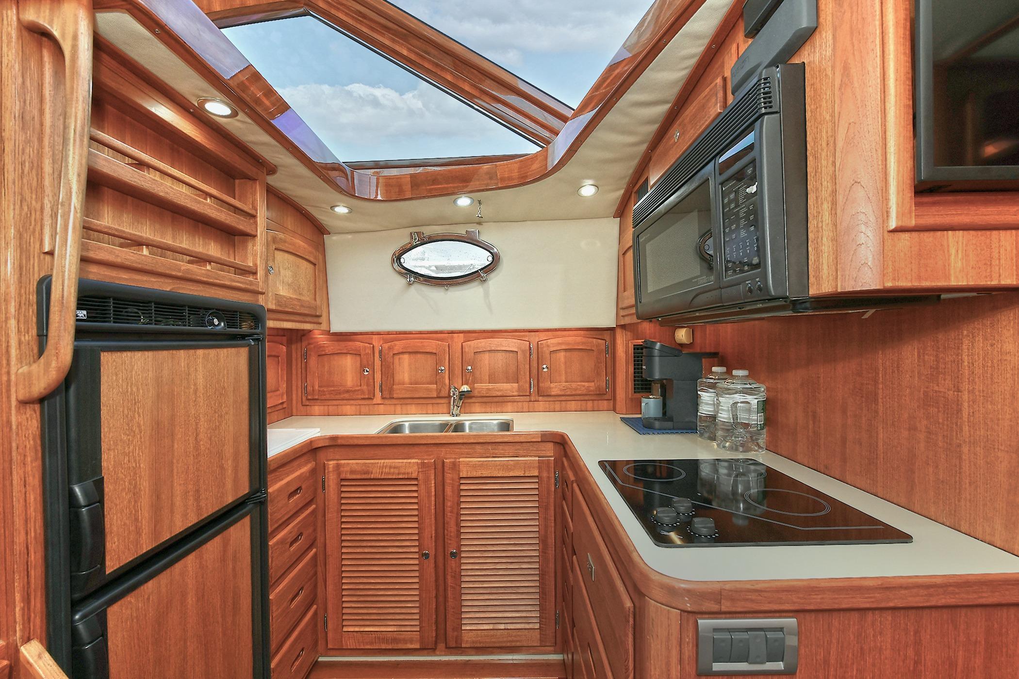 Luxurious 2005 San Juan Downeast Express yacht kitchen with wood cabinetry and modern appliances.