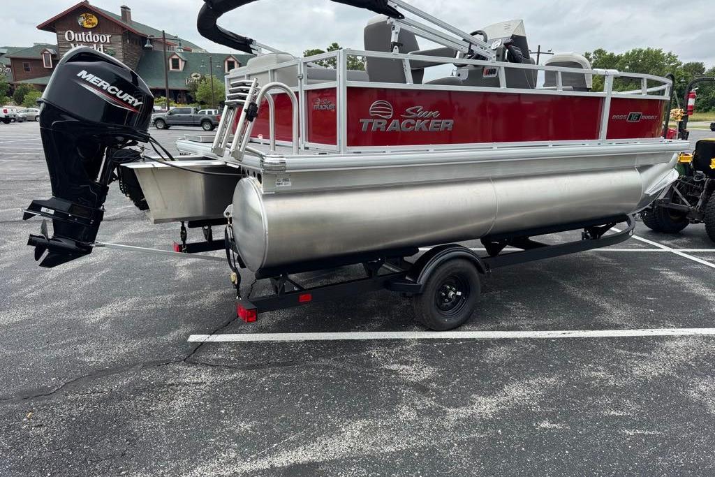 2026 Sun Tracker Bass Buggy 16 XL Select pontoon boat with Mercury engine in parking lot.