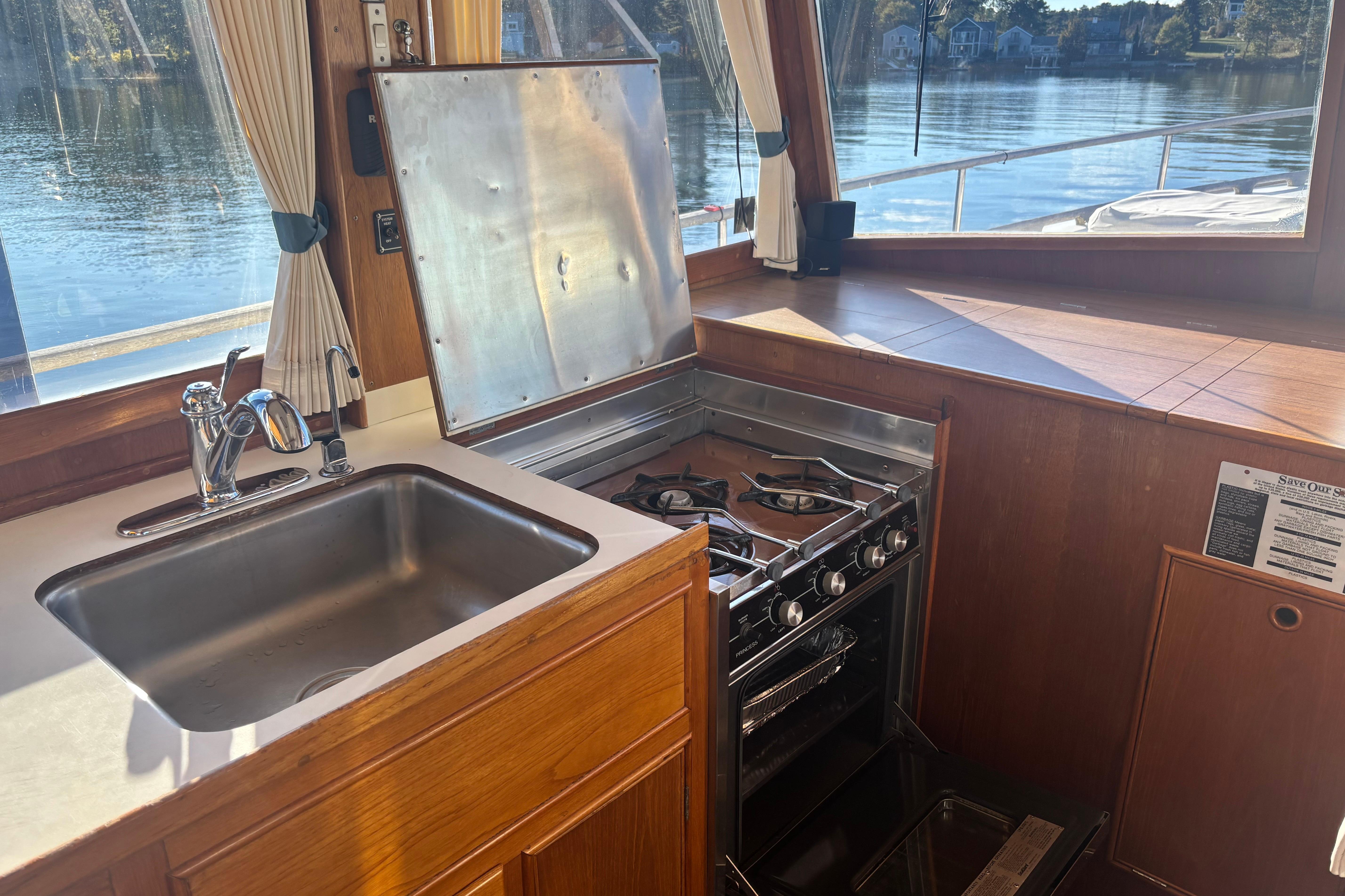 Galley kitchen in 1989 Grand Banks 46 Classic yacht with stove and sink, overlooking water.
