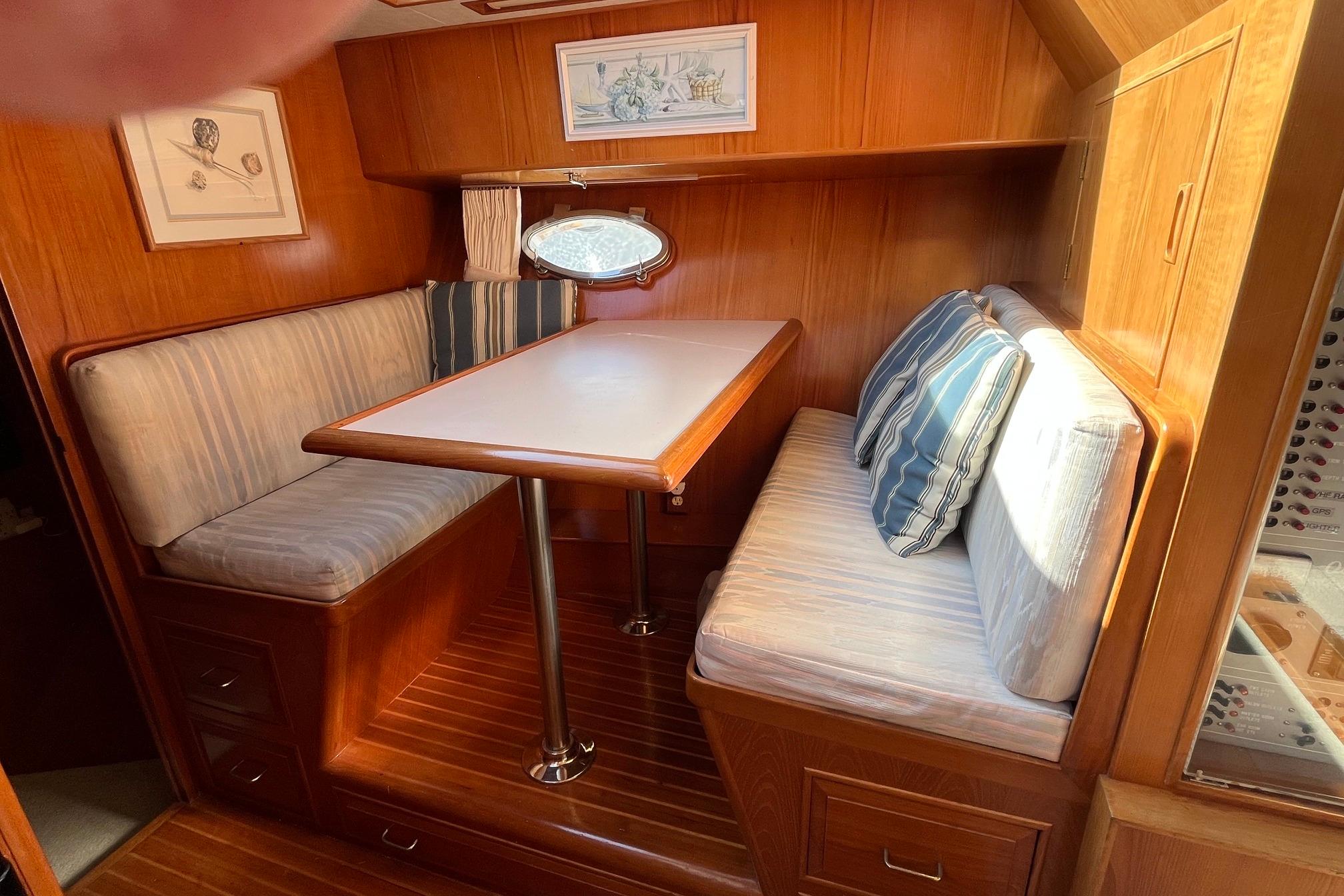 Cozy dining area in 1989 Ocean Alexander 440 Sundeck CPMY with wood finish and striped cushions.