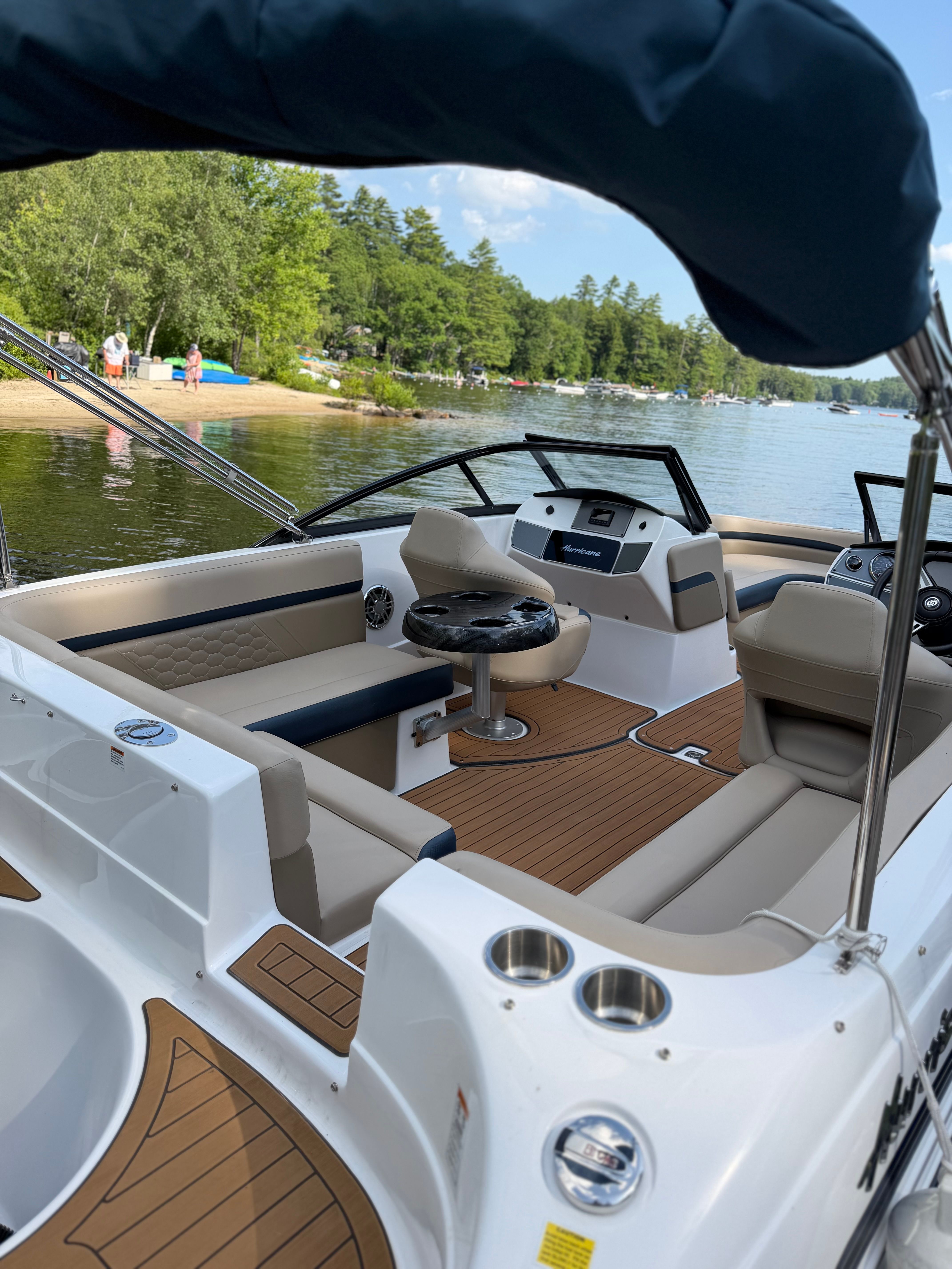 The image shows the cockpit of a 2022 Hurricane SunDeck 217 OB with beige seating and wood flooring.