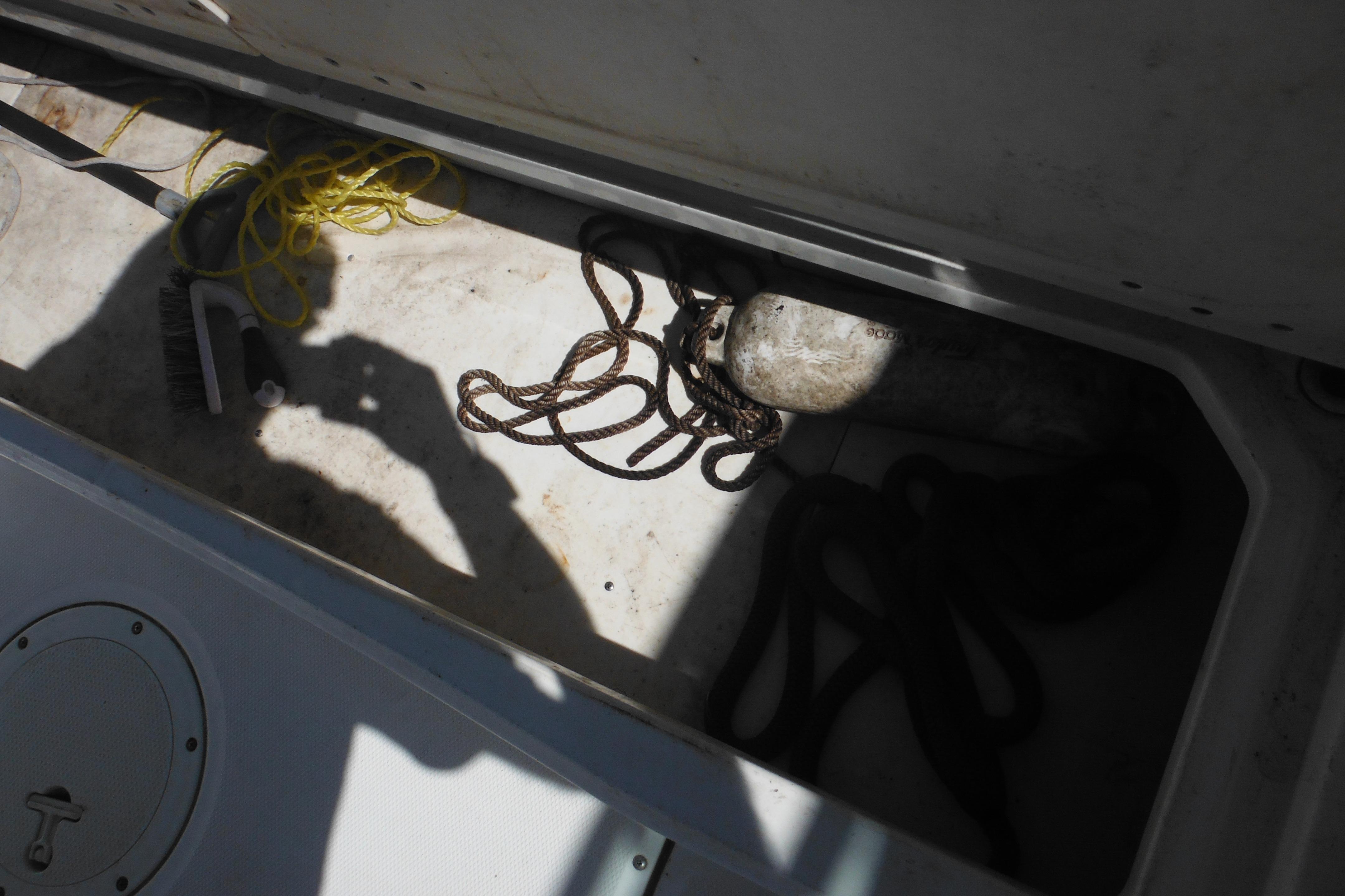Storage compartment of a 2009 Boston Whaler 200 Dauntless with ropes and cleaning brush.