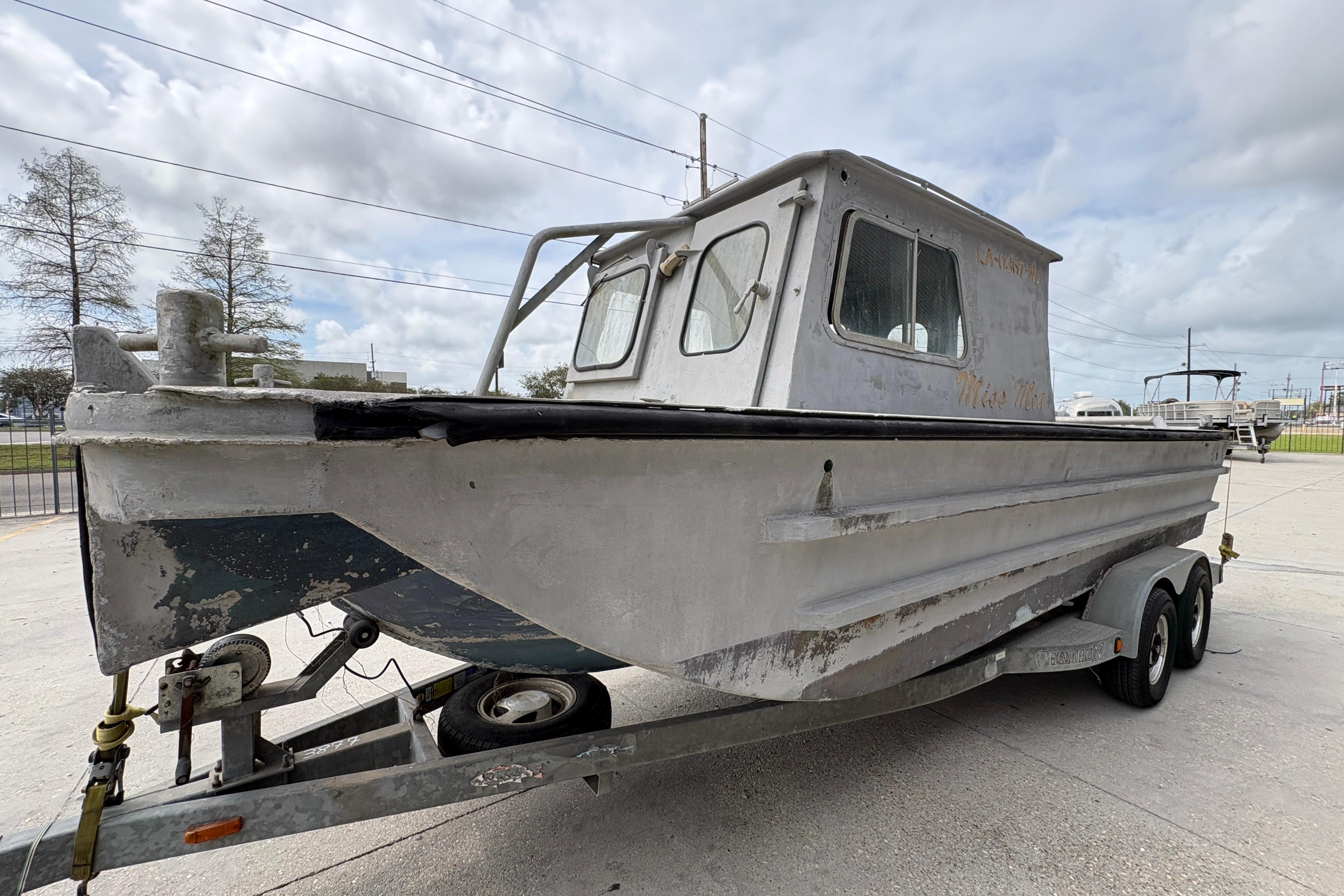 Vintage 1972 custom 23' work/push boat on trailer, weathered exterior, cloudy sky background.