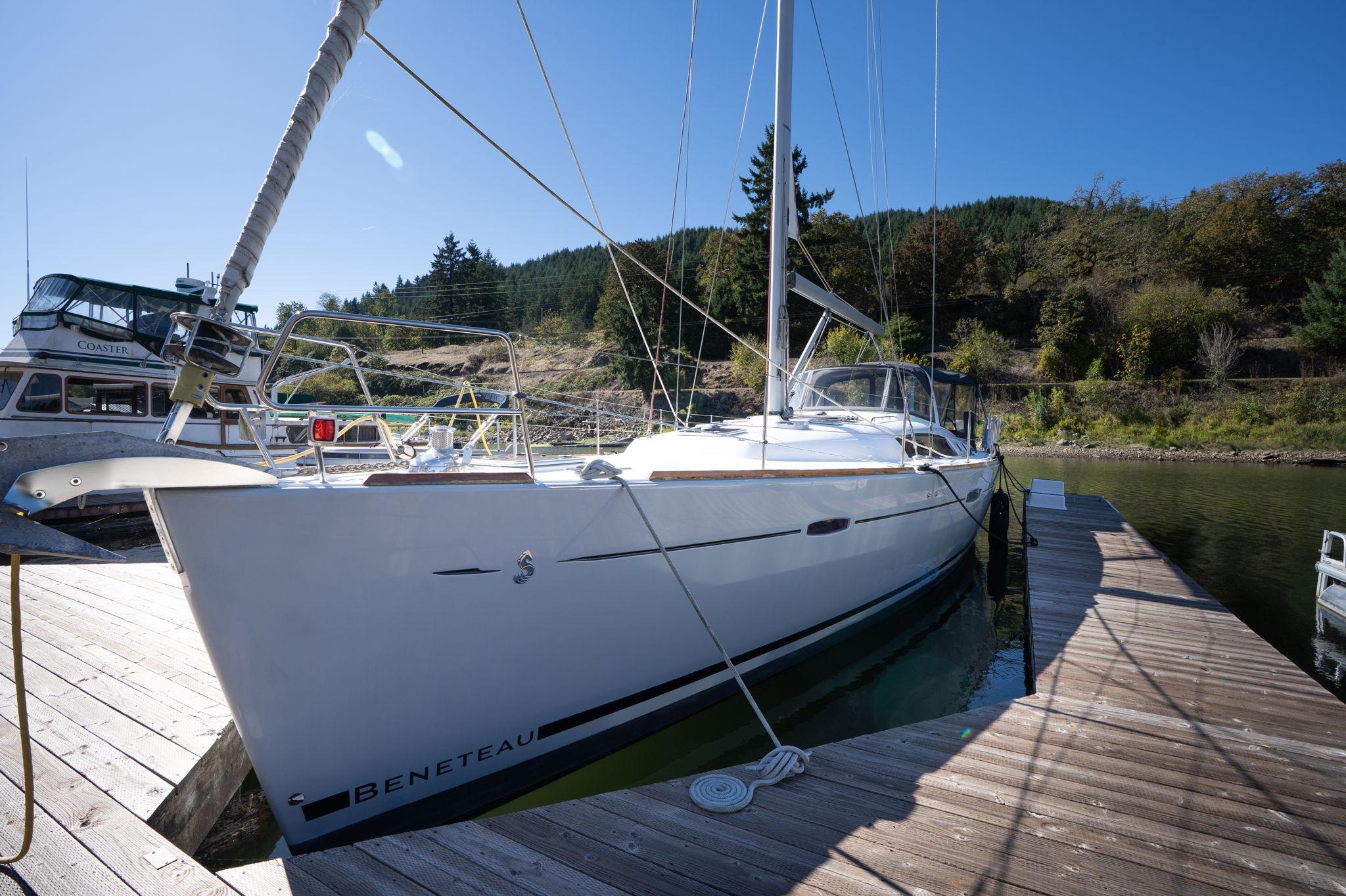 2013 Beneteau Oceanis 50 sailboat docked at a marina, surrounded by lush greenery.