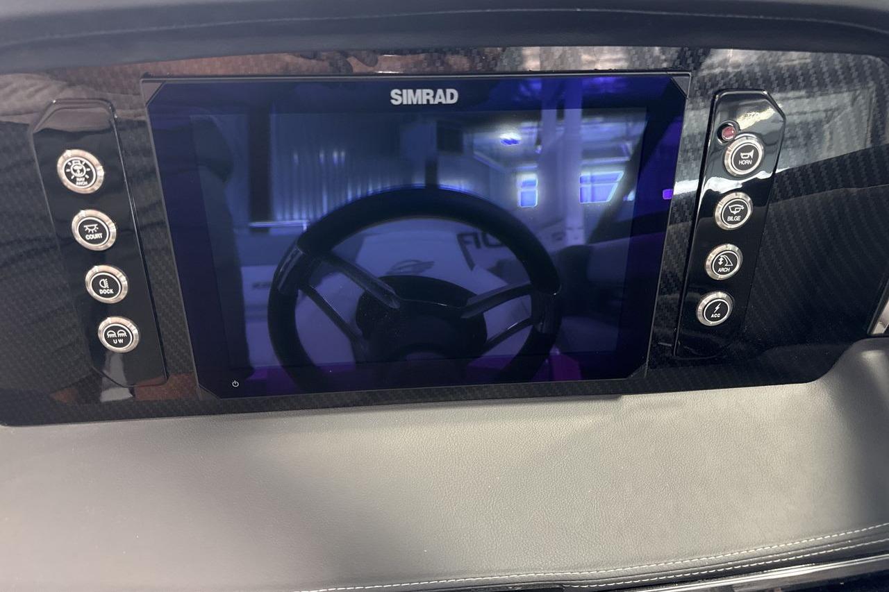 The image shows a modern boat cockpit with a Simrad display and various controls.