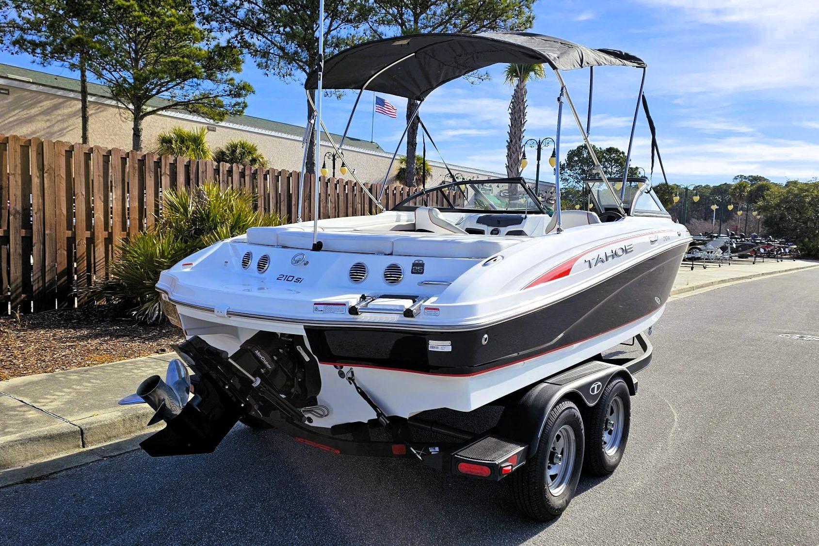 2023 Tahoe 210 Si boat on trailer, parked outdoors, with canopy and sleek design.