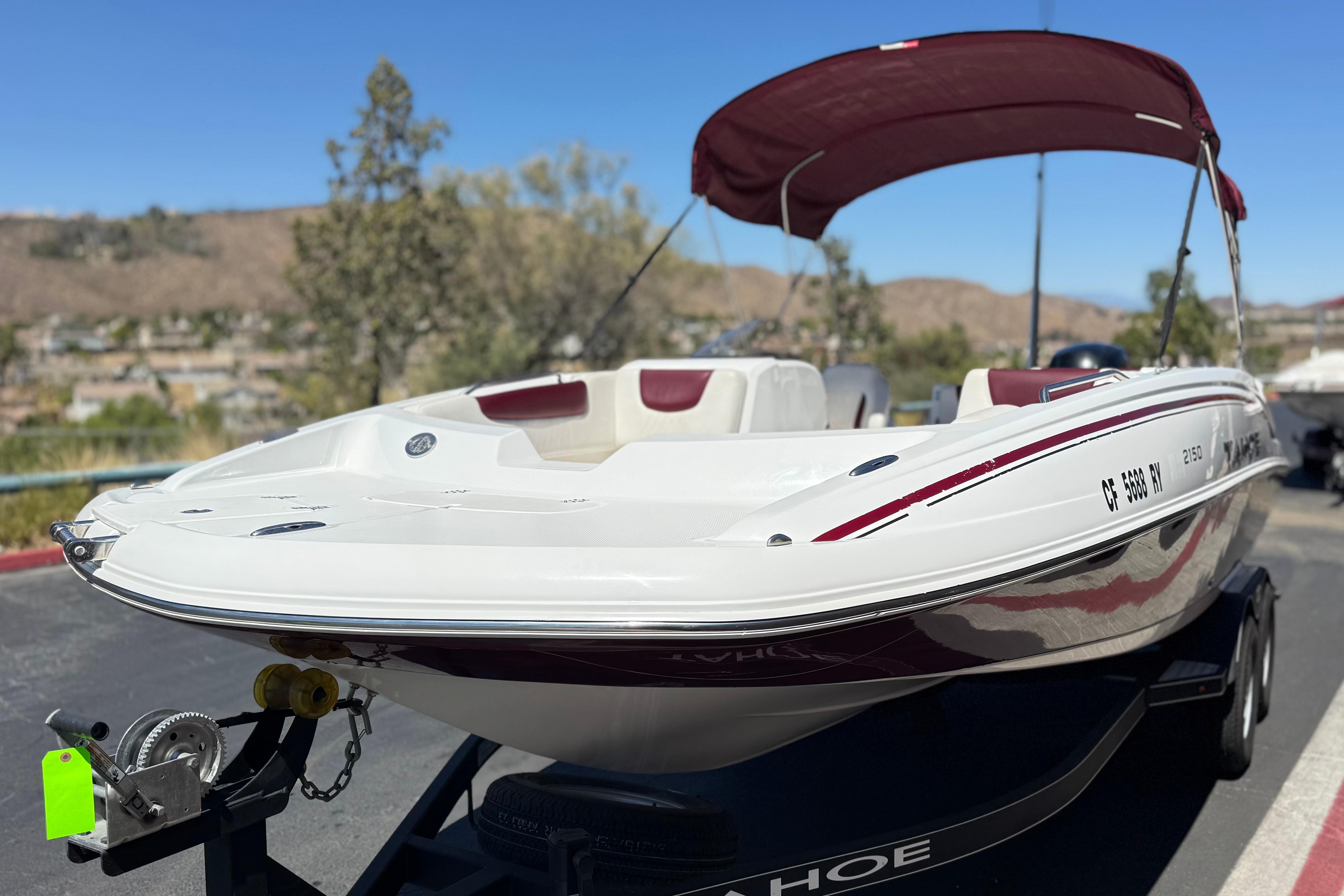2017 Tahoe 2150 boat with maroon canopy on trailer, parked outdoors.