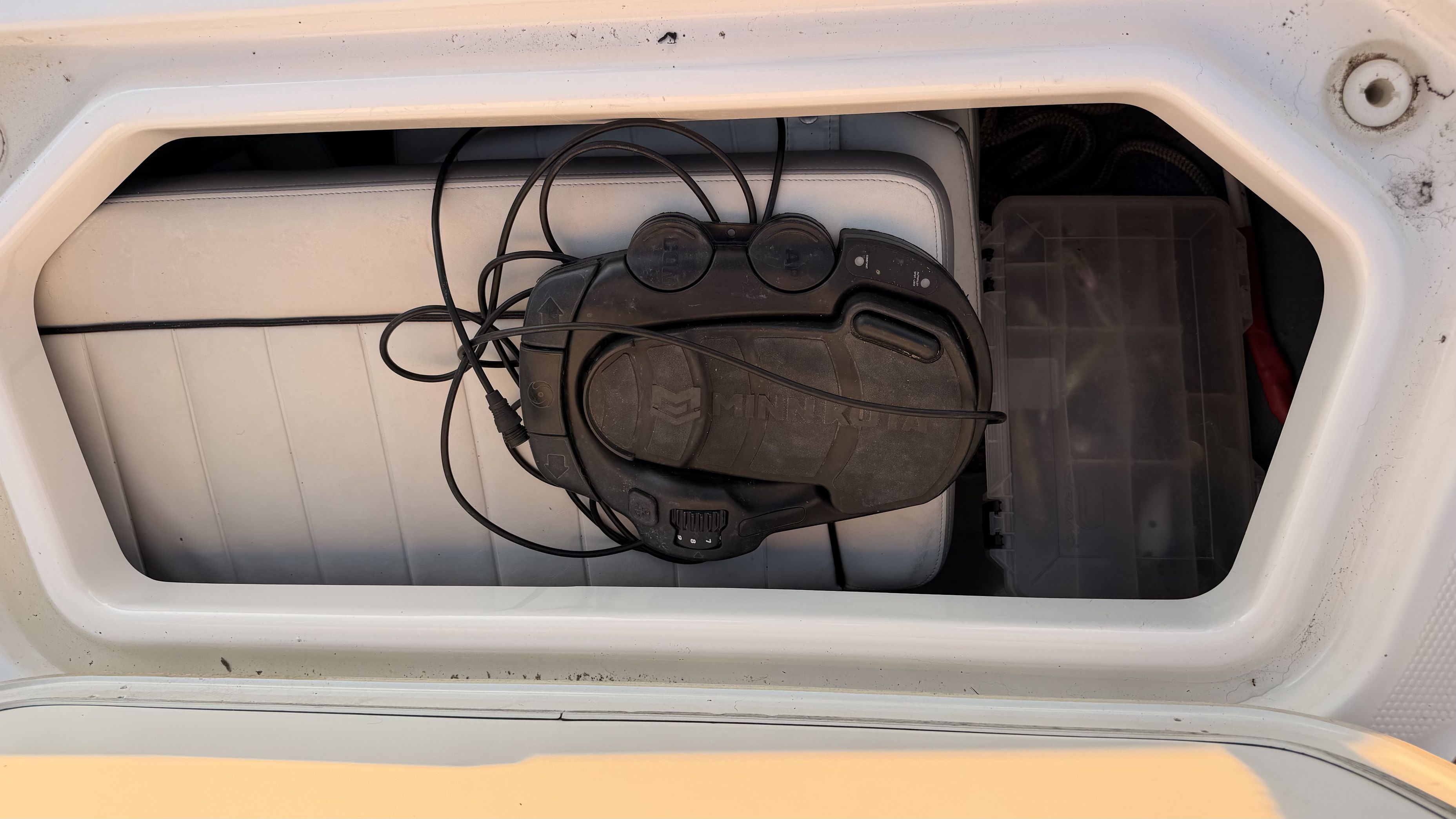 A storage compartment on a boat with cables and a box.
