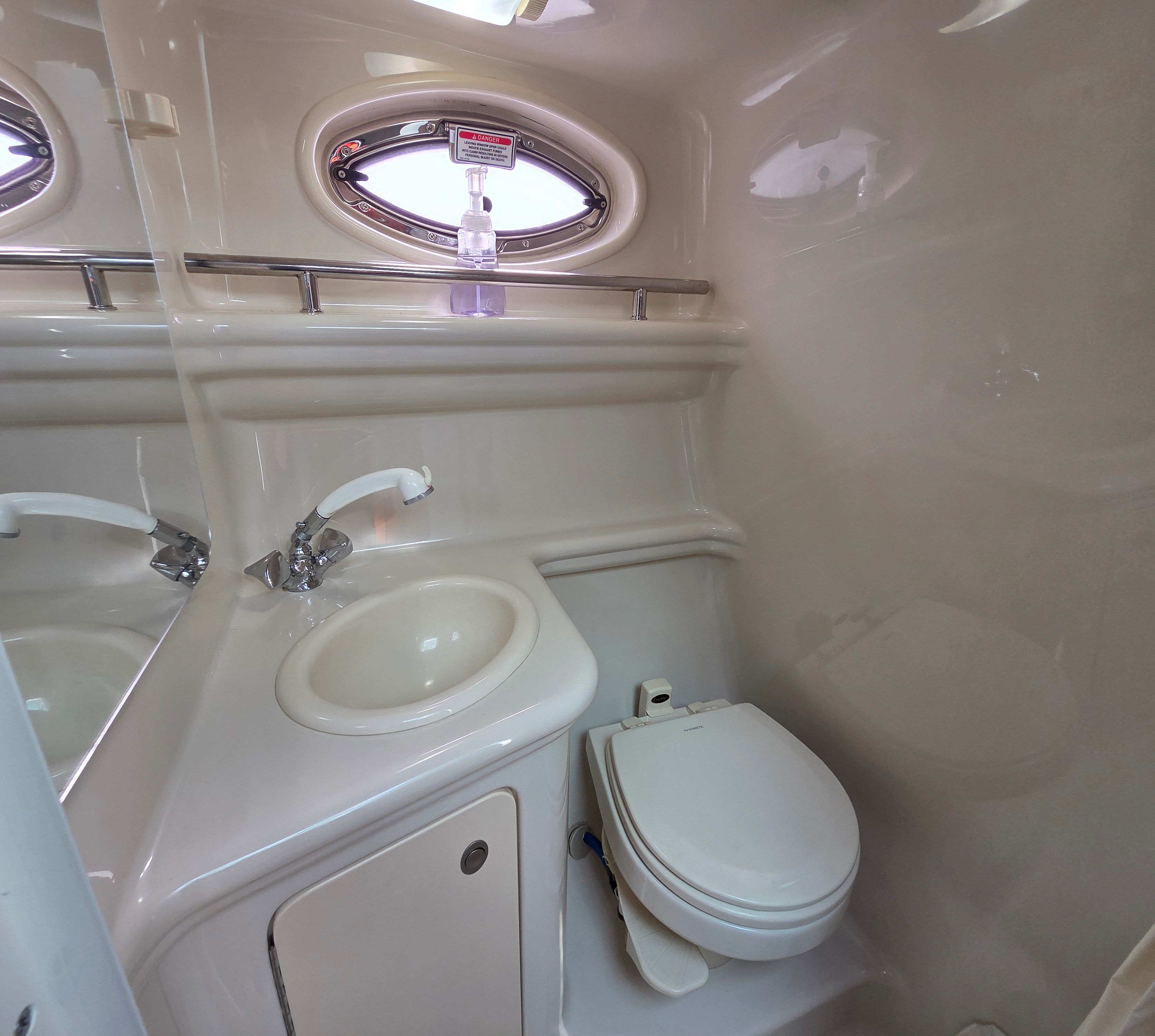 Bathroom in a 2005 Sea Ray Sundancer 260 with sink, toilet, and porthole.
