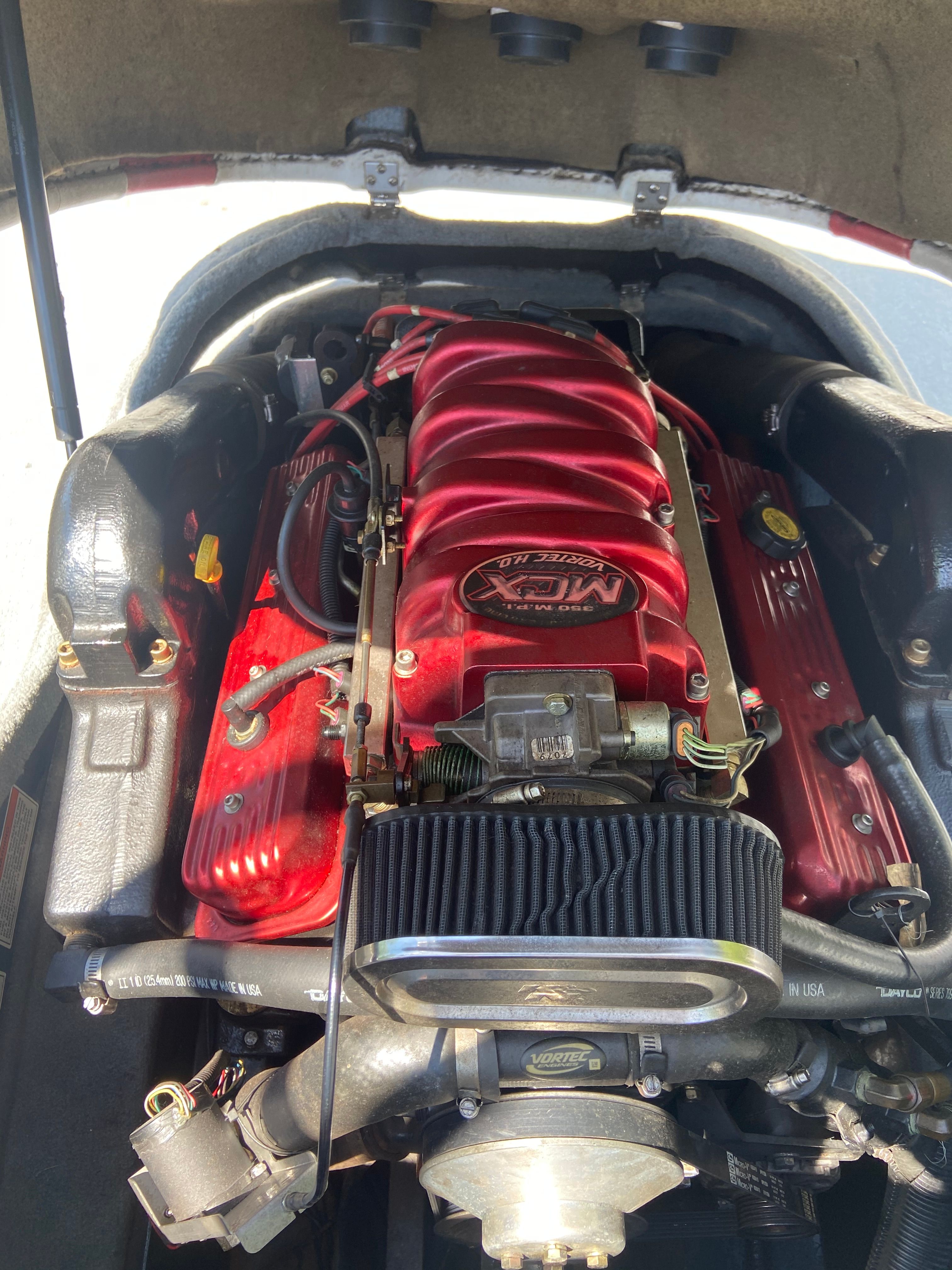 The engine of a 2004 MasterCraft X-9 boat with red covers and visible components.