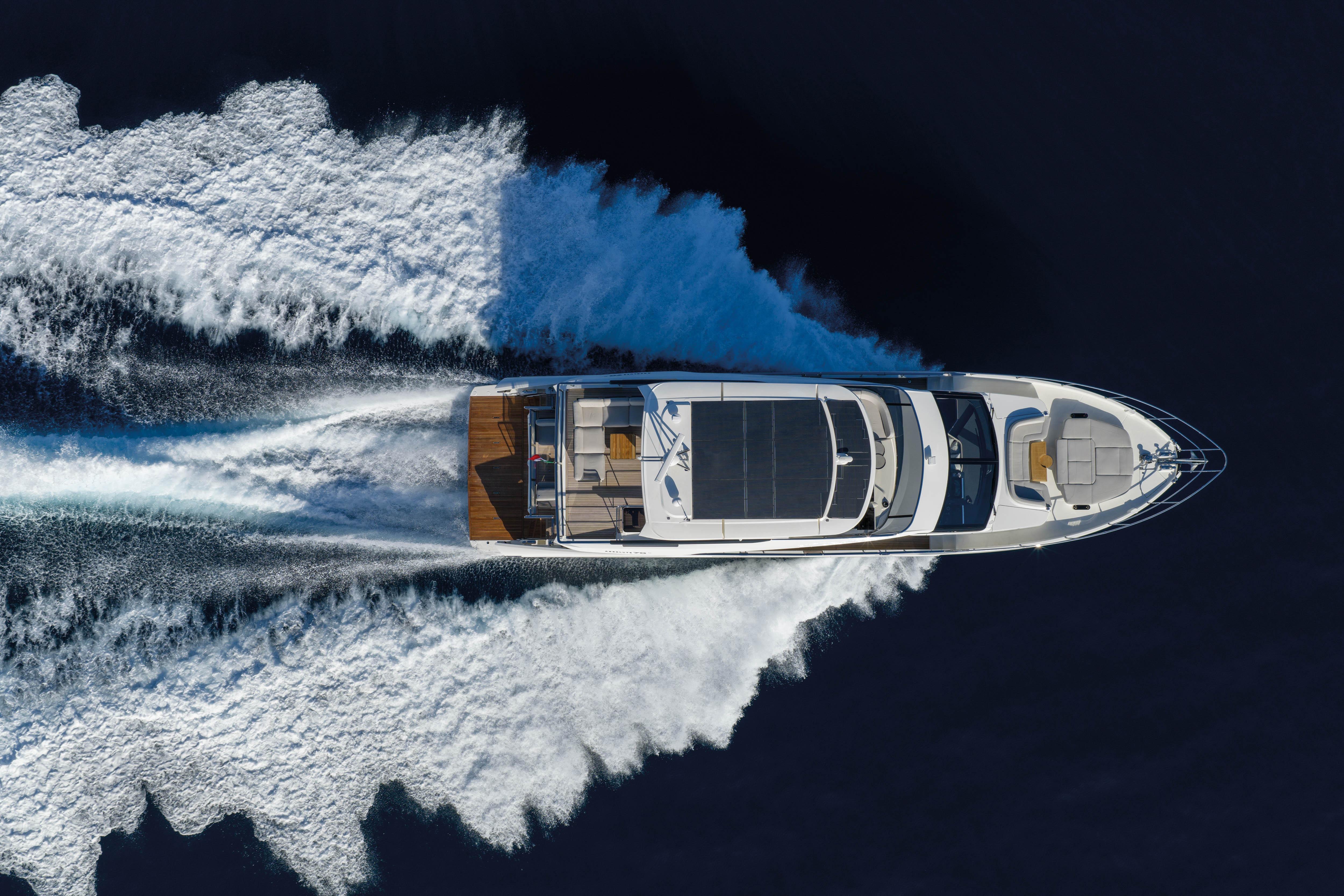 Luxury yacht speeding over water, leaving a trail of white wake.