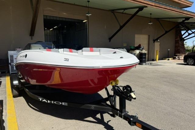 2026 Tahoe T16 boat with red hull on trailer, parked outside a building.
