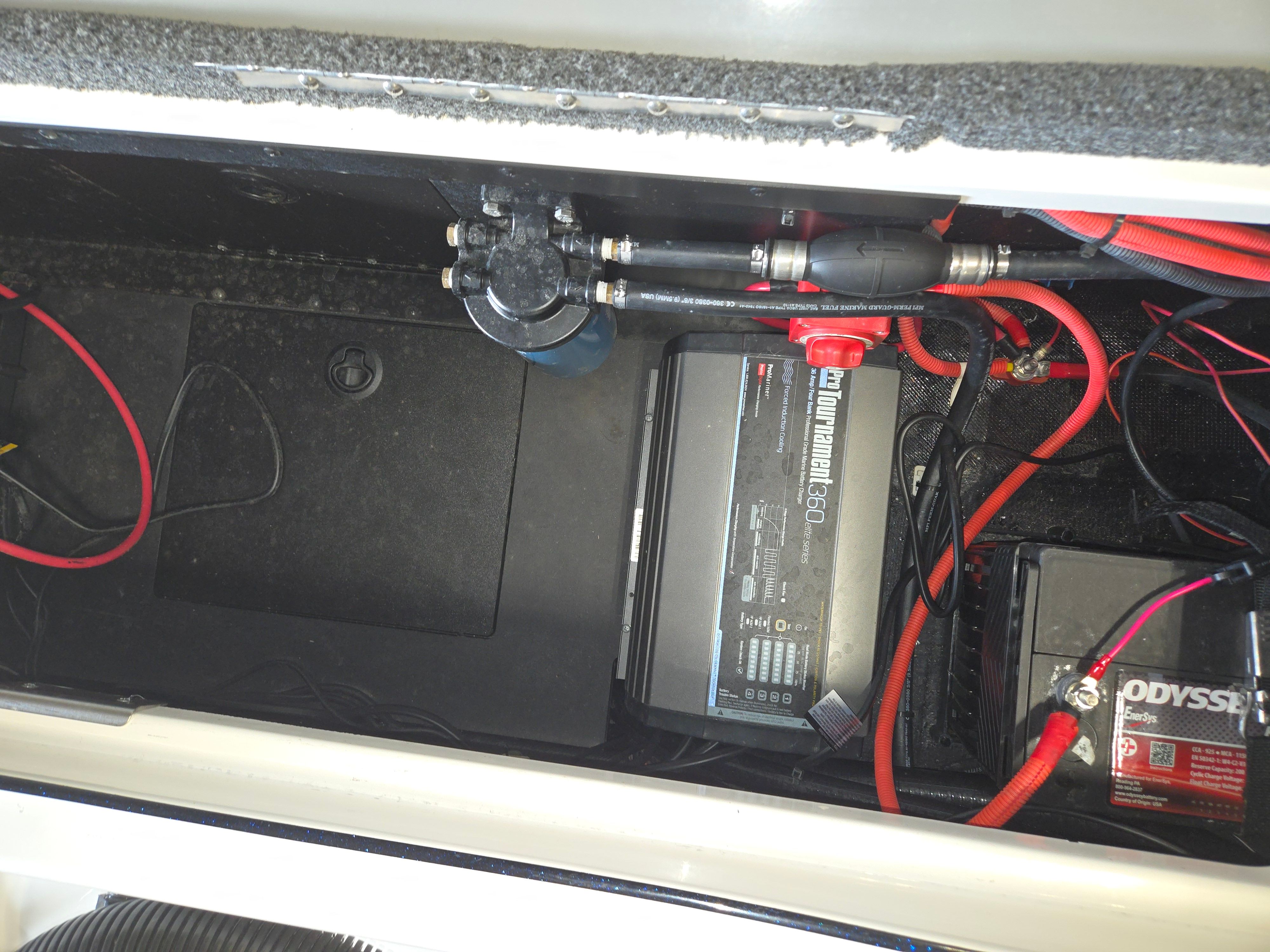 View inside a boat with batteries and wiring in the storage compartment.