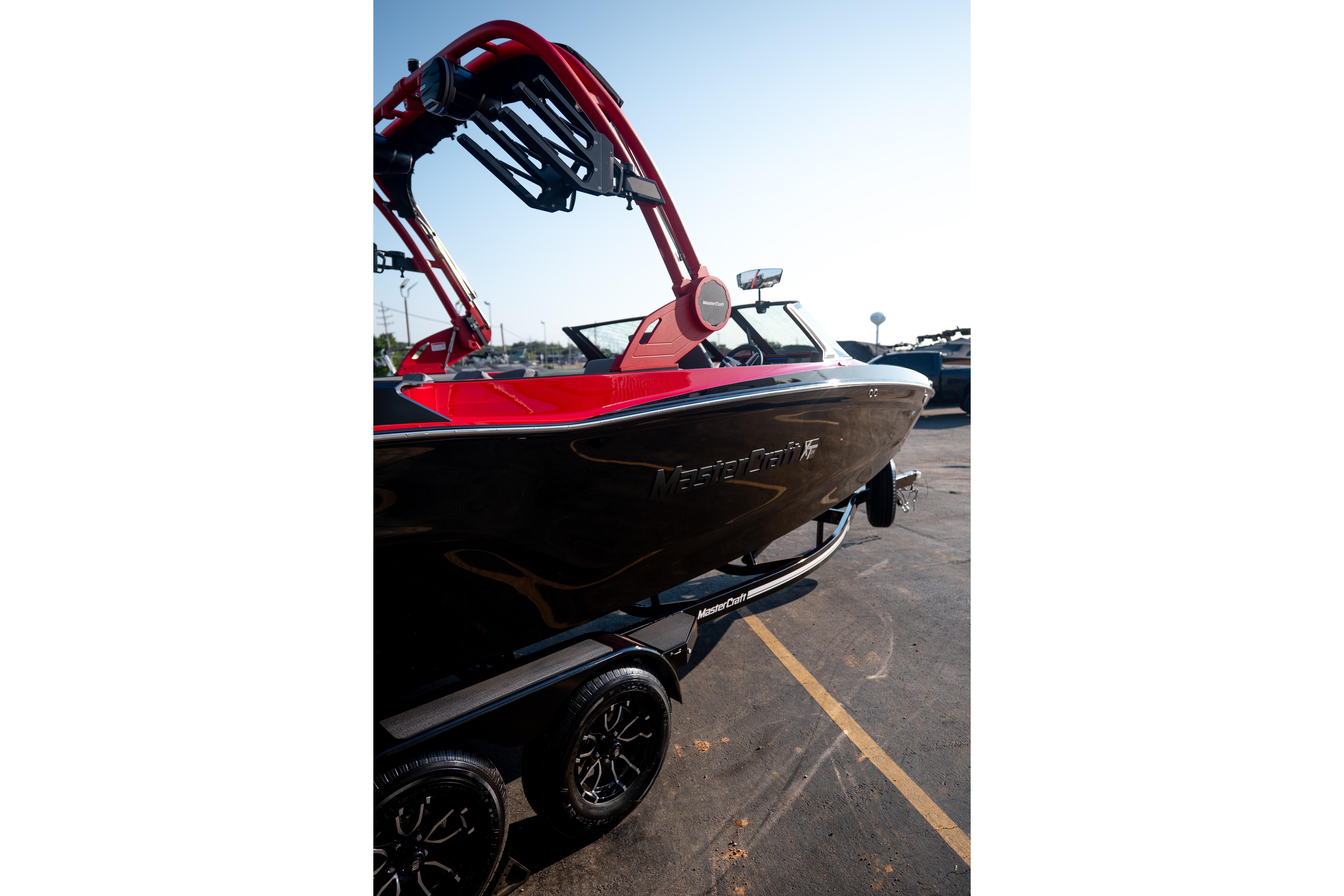 2027 MasterCraft XT24 boat with red accents on a trailer in a parking lot.