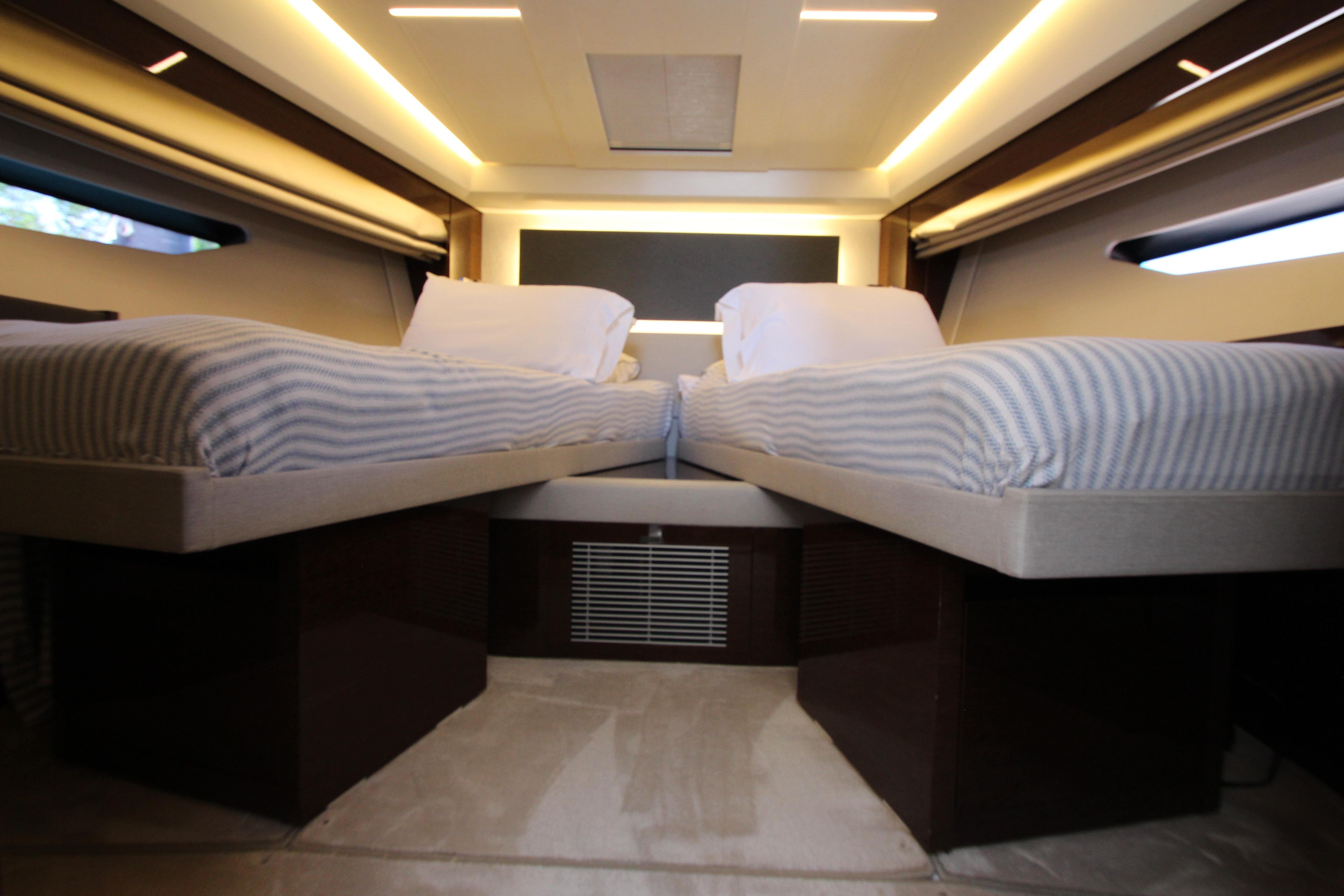 Luxurious twin beds in a 2022 Prestige 520 yacht cabin, featuring modern lighting and sleek design.