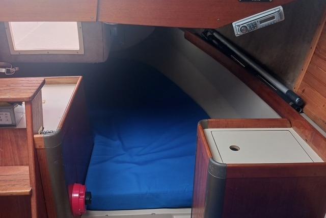Interior cabin of a 1989 O'Day 272 sailboat with blue bedding.