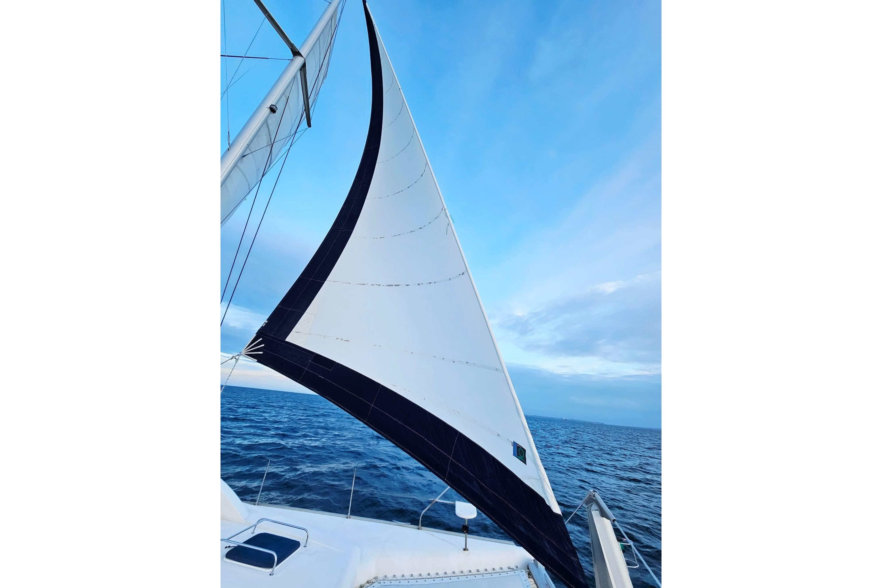 Sailing on a 2007 Leopard 43 catamaran with white sails against a blue sky.