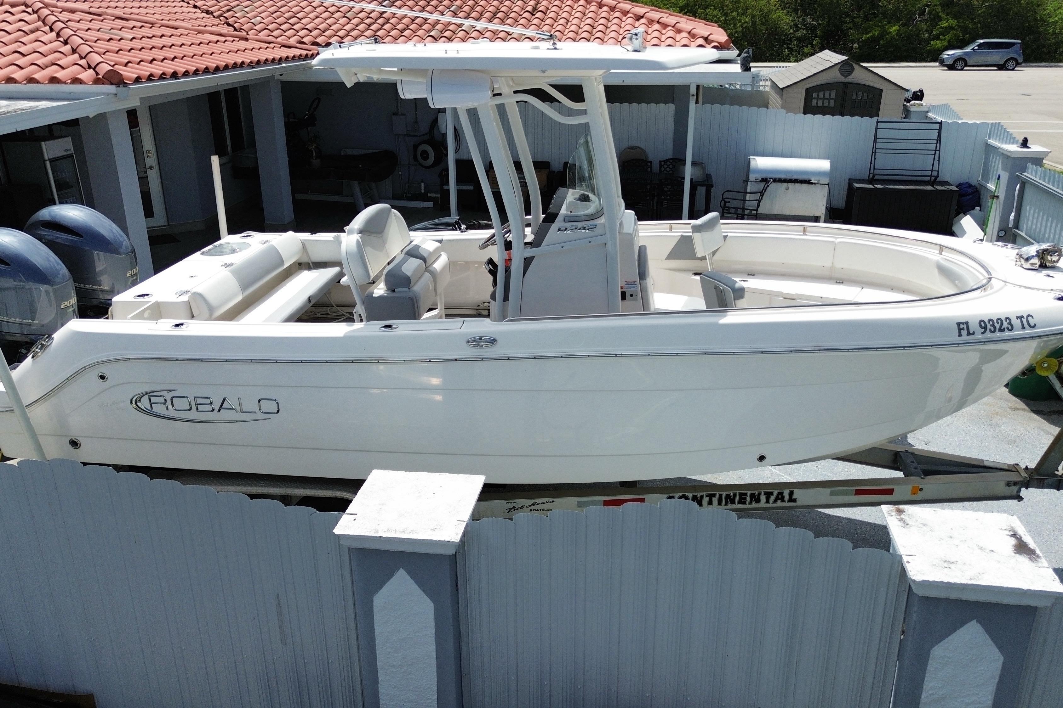 2022 Robalo R242 Center Console boat on trailer, parked near a house.