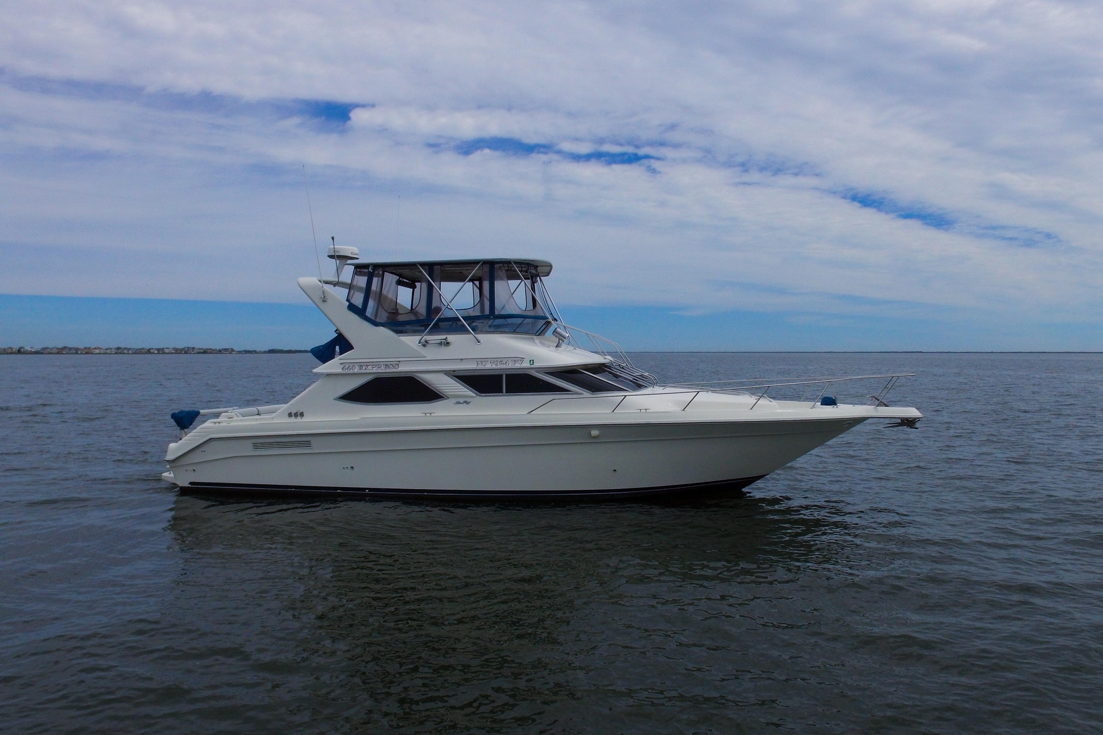 1993 Sea Ray 440 Express Bridge yacht on calm waters under a cloudy sky.