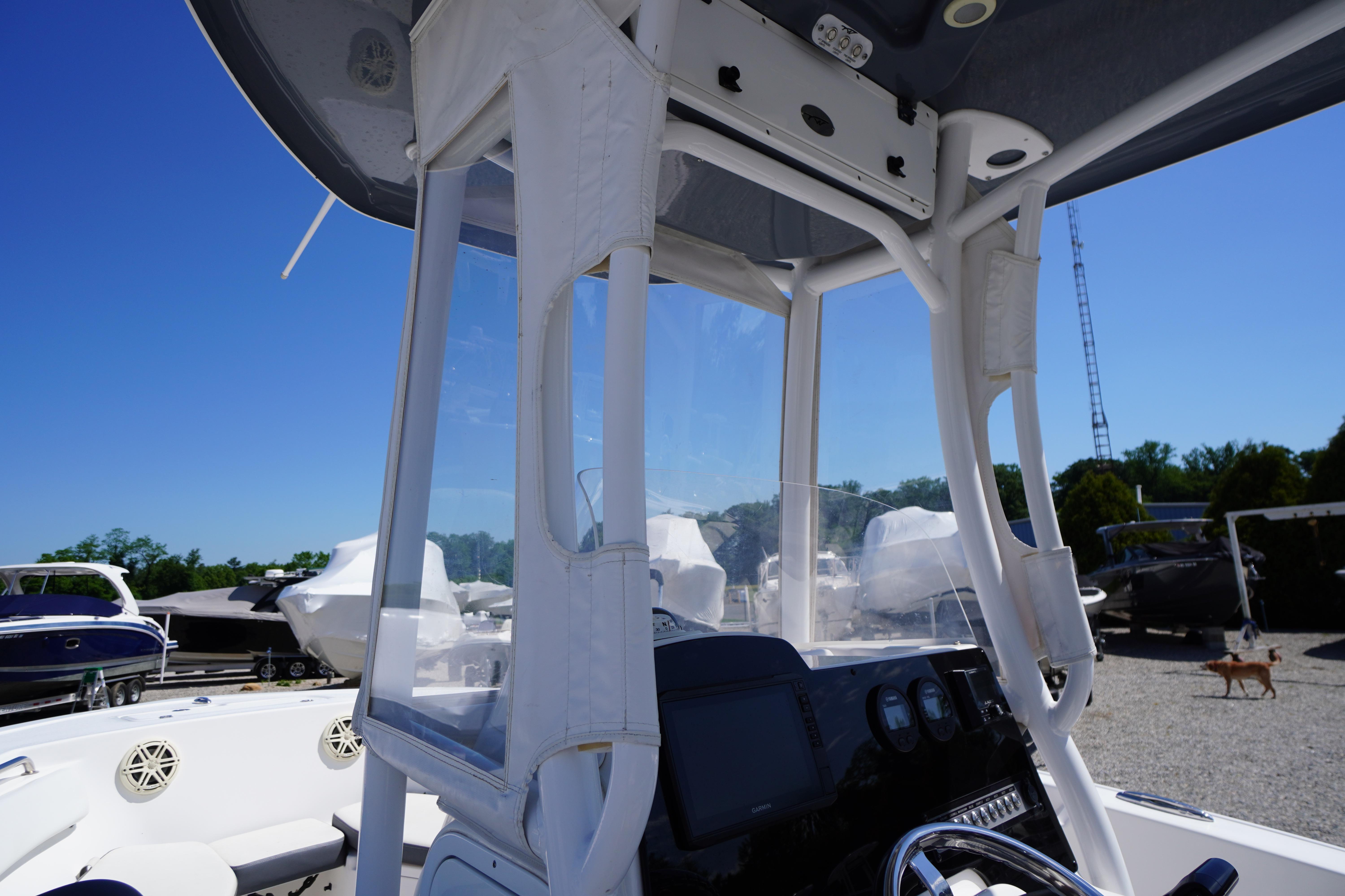 2020 Tidewater 220 LXF boat interior with console and clear enclosure, parked outdoors.