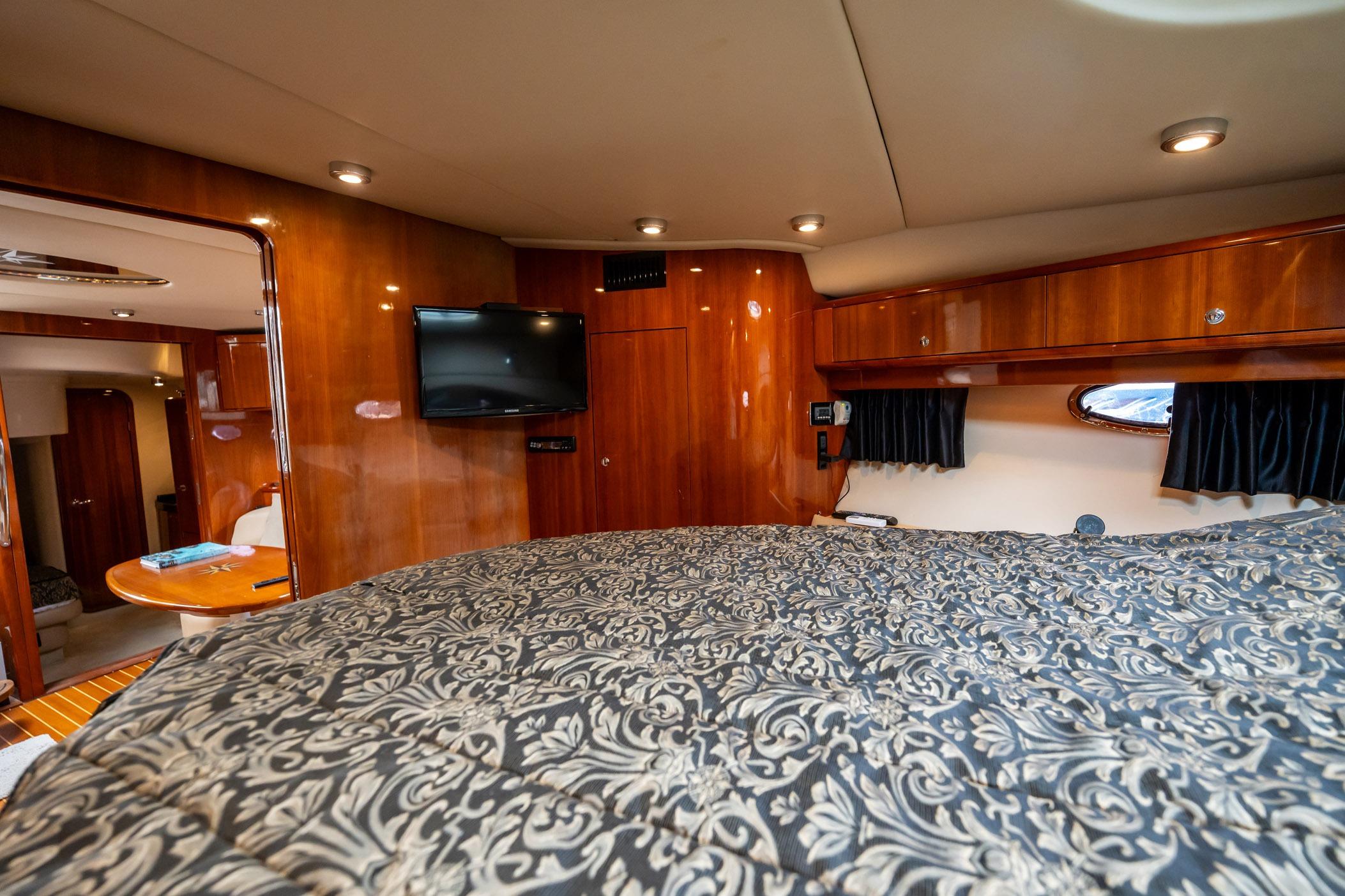 Luxurious interior of 2008 Regal Commodore 4460 yacht with wood paneling and patterned bedding.