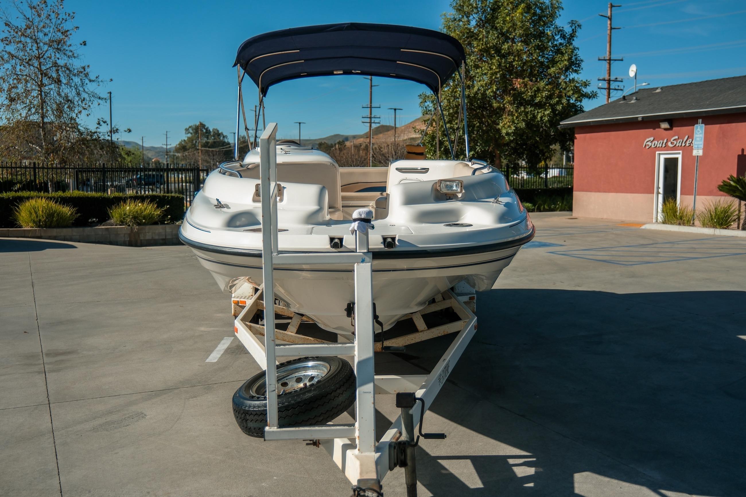 1998 Chaparral 232 Sunesta boat on trailer at dealership parking lot.