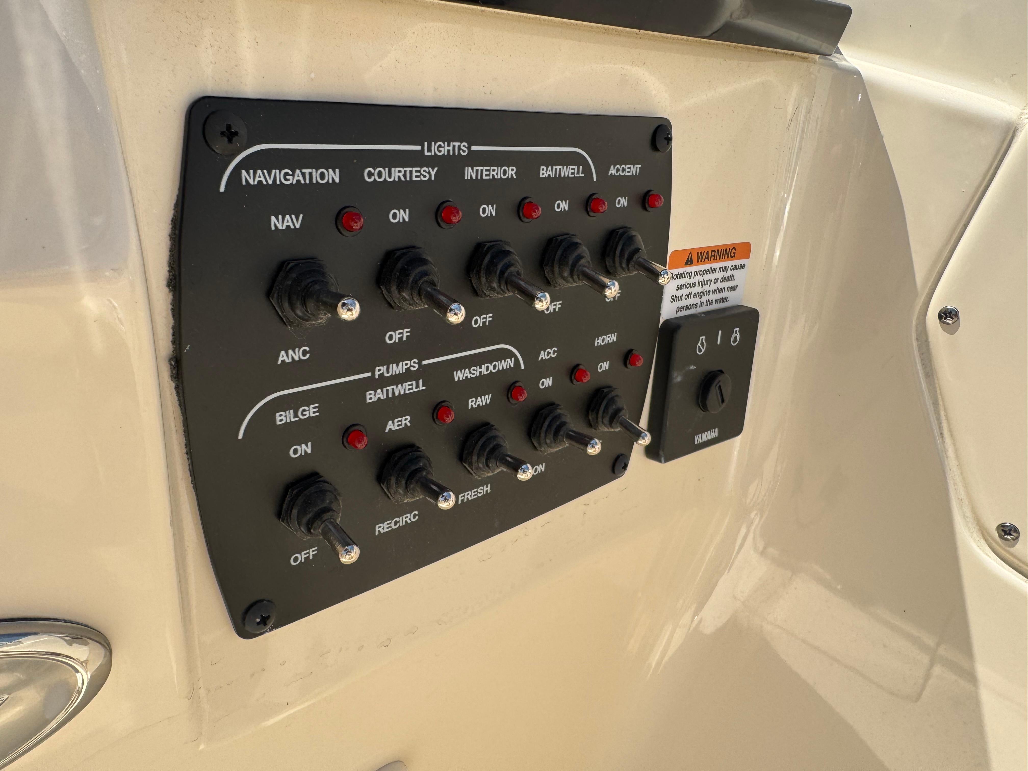 Control panel of 2025 Scout 215 Dorado boat with labeled switches and warning label.