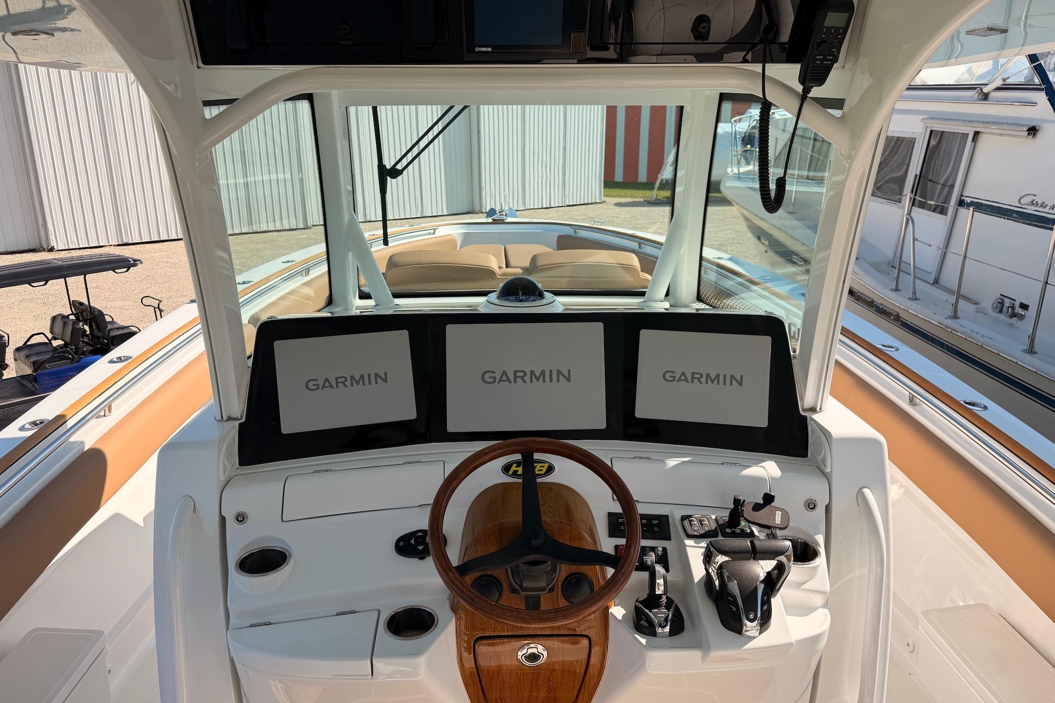 Cockpit of 2022 HCB 42 Lujo boat with Garmin navigation displays and wooden steering wheel.