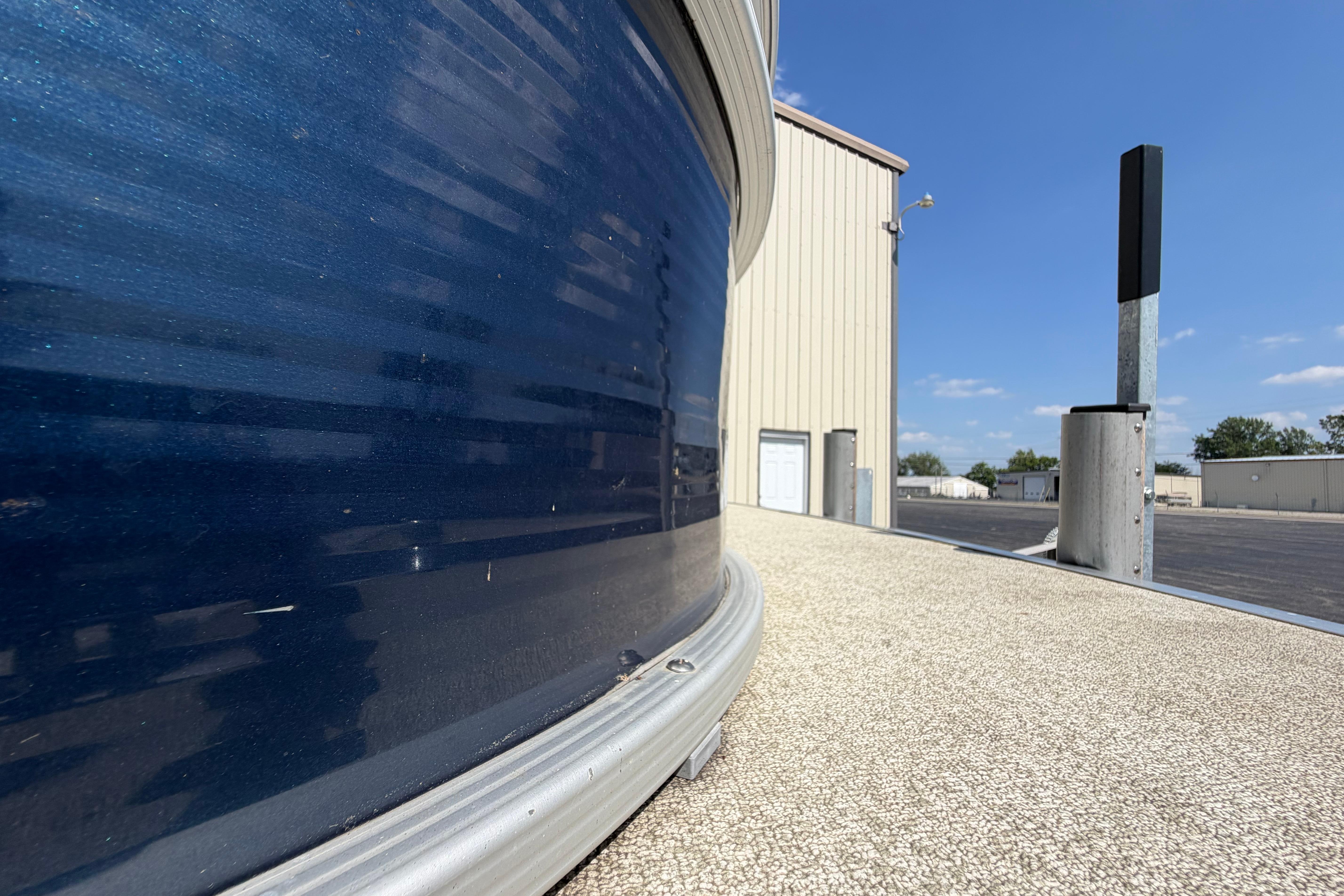 2017 Bennington 25 SSXAPG pontoon boat docked near a warehouse under clear blue skies.