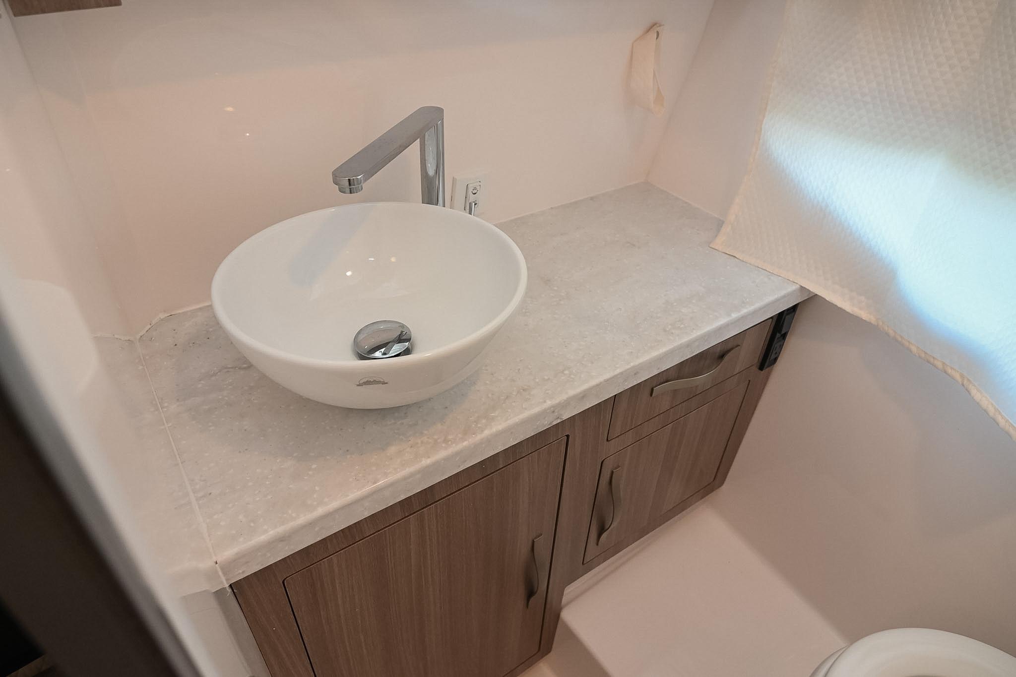 Modern bathroom sink in 2021 Regal 33 Express yacht, featuring sleek faucet and wooden cabinetry.