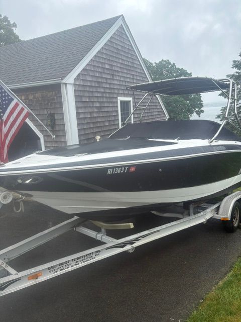 A 2003 Cobalt 240 boat on a trailer in front of a shingled house.
