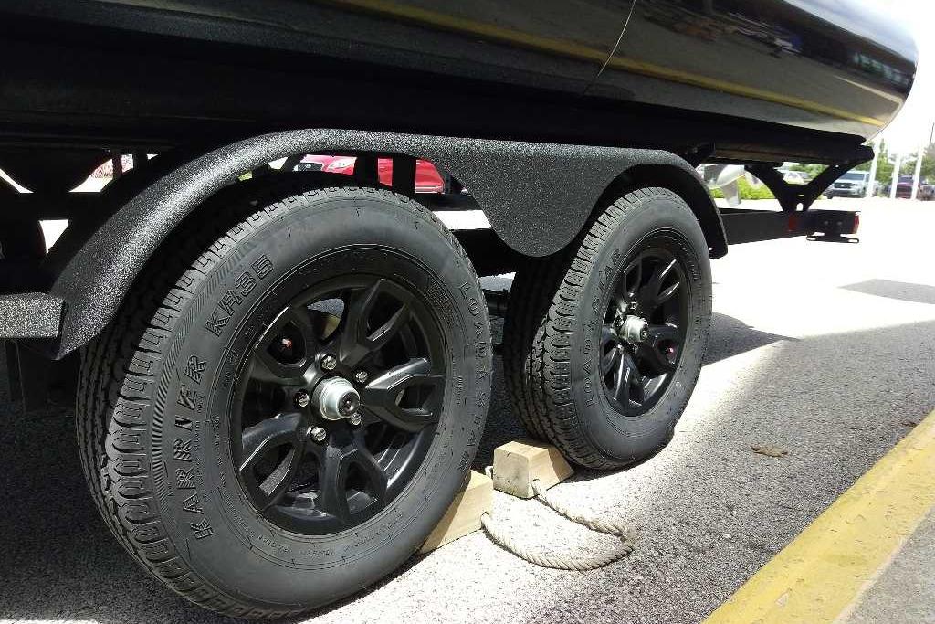 Trailer wheels of a 2026 Regency 230 DL, secured with wooden chocks.