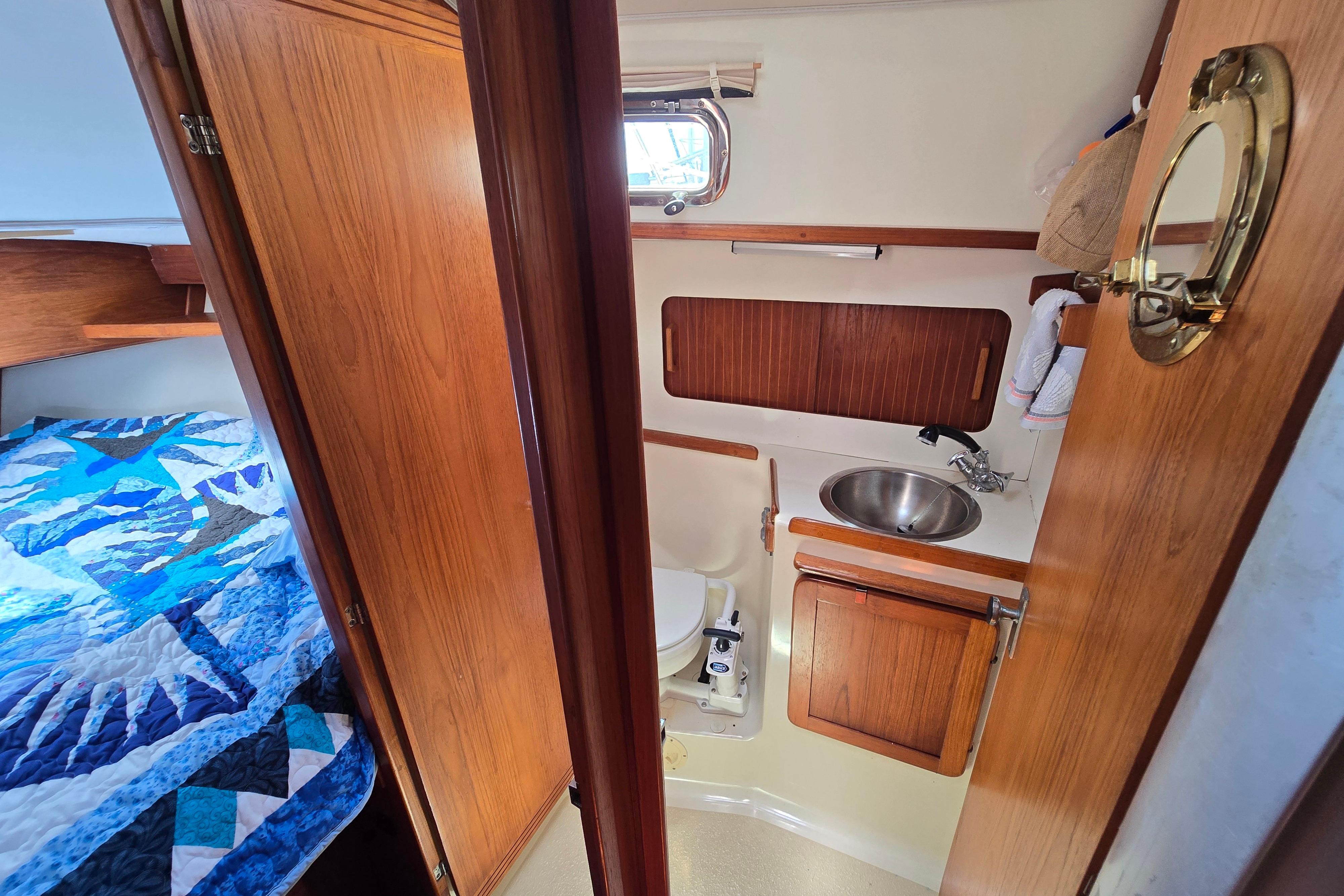 1993 Caliber 35 yacht interior with wooden cabinetry, compact bathroom, and cozy sleeping area.