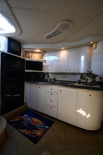 Interior of 1997 Sea Ray 400 Sundancer yacht kitchen with white cabinets and appliances.