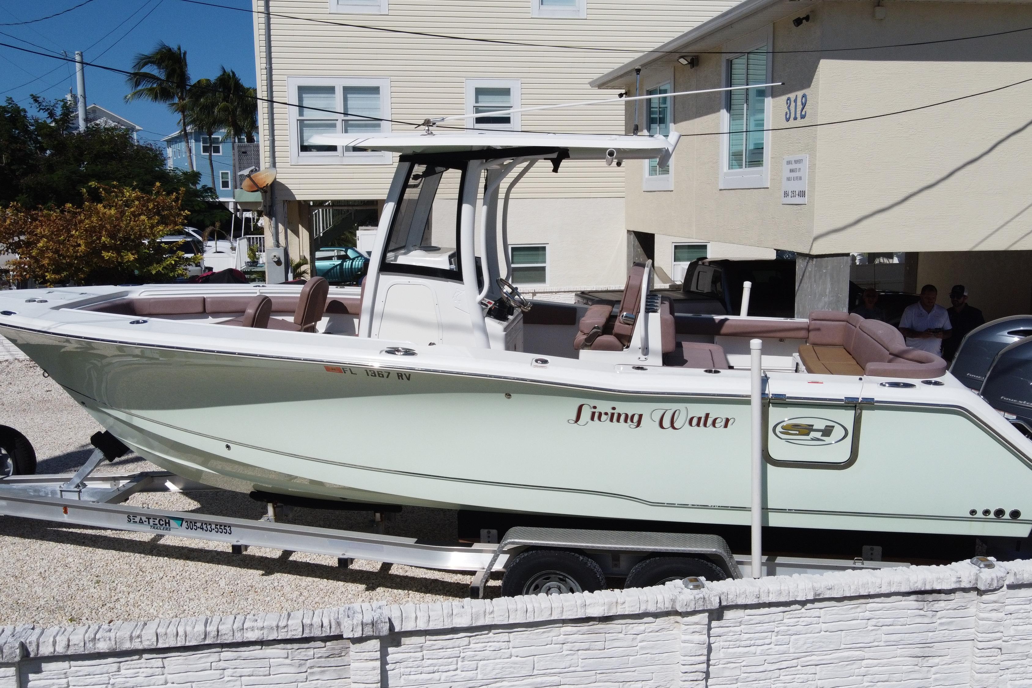 2019 Sea Hunt Ultra 275 SE boat on trailer, labeled "Living Water," parked near a building.