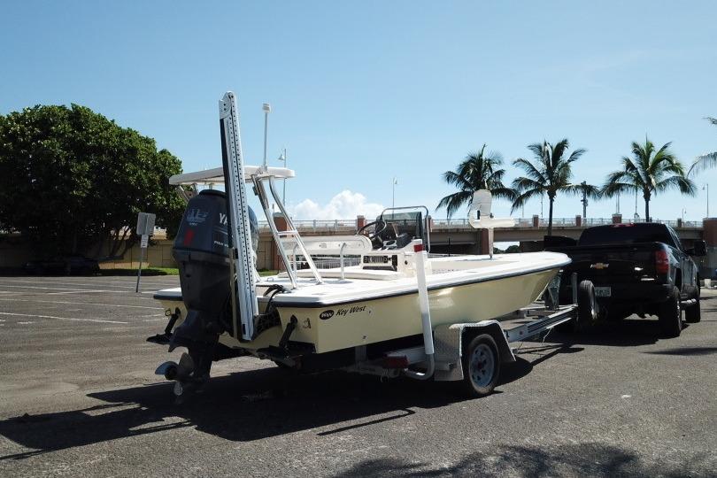 2002 Key West 1760 Stealth boat on trailer, parked near palm trees under clear sky.