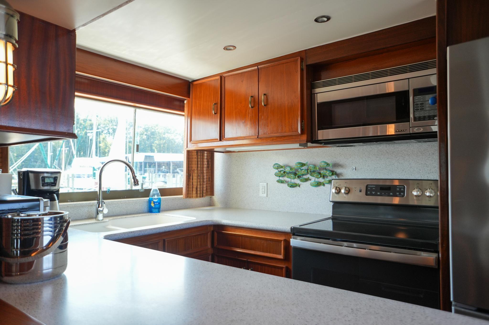 Interior kitchen of 1980 Hatteras 70 Motor Yacht with modern appliances and wooden cabinetry.