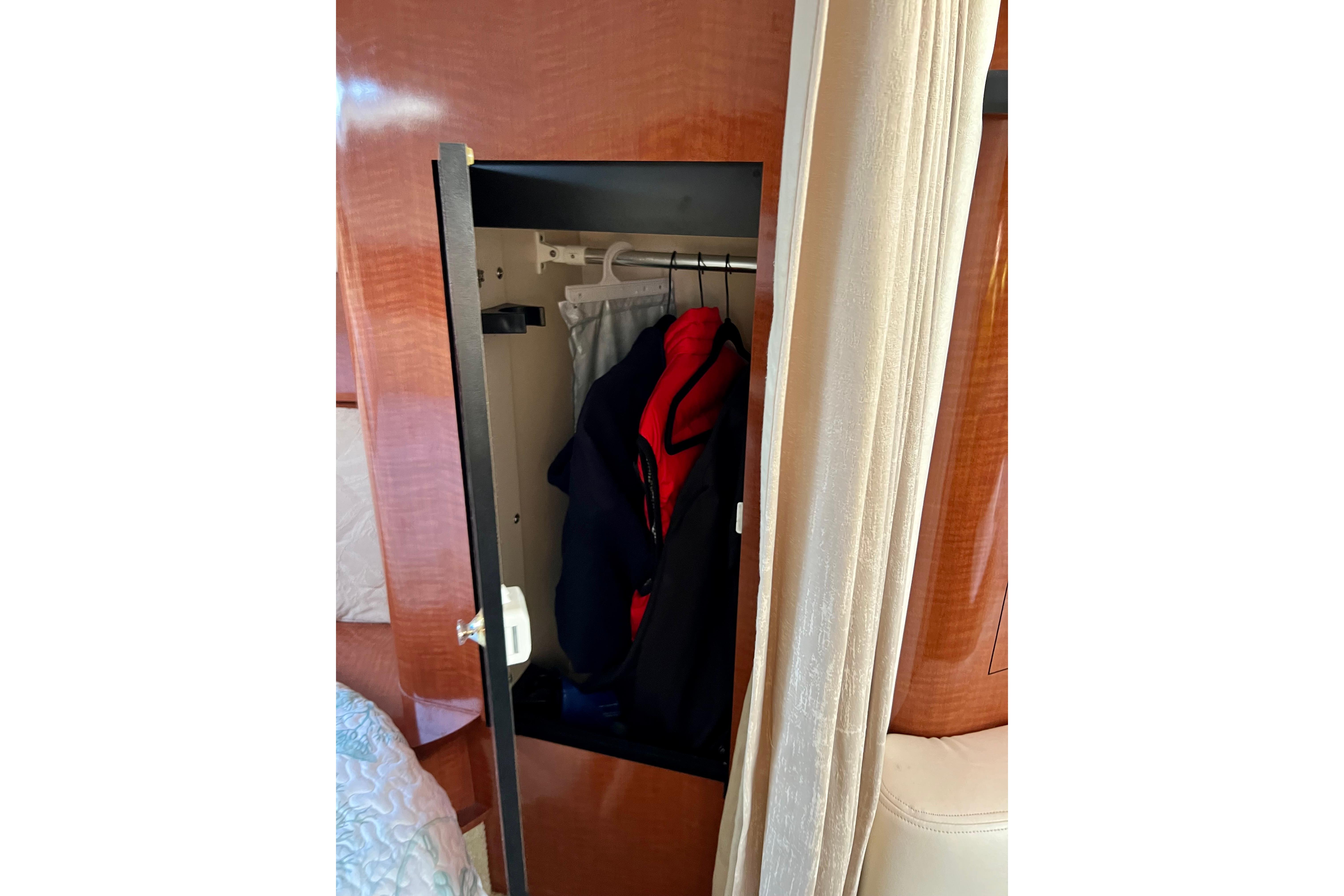 Open closet with clothes inside on a 2004 Sea Ray 320 Sundancer yacht.