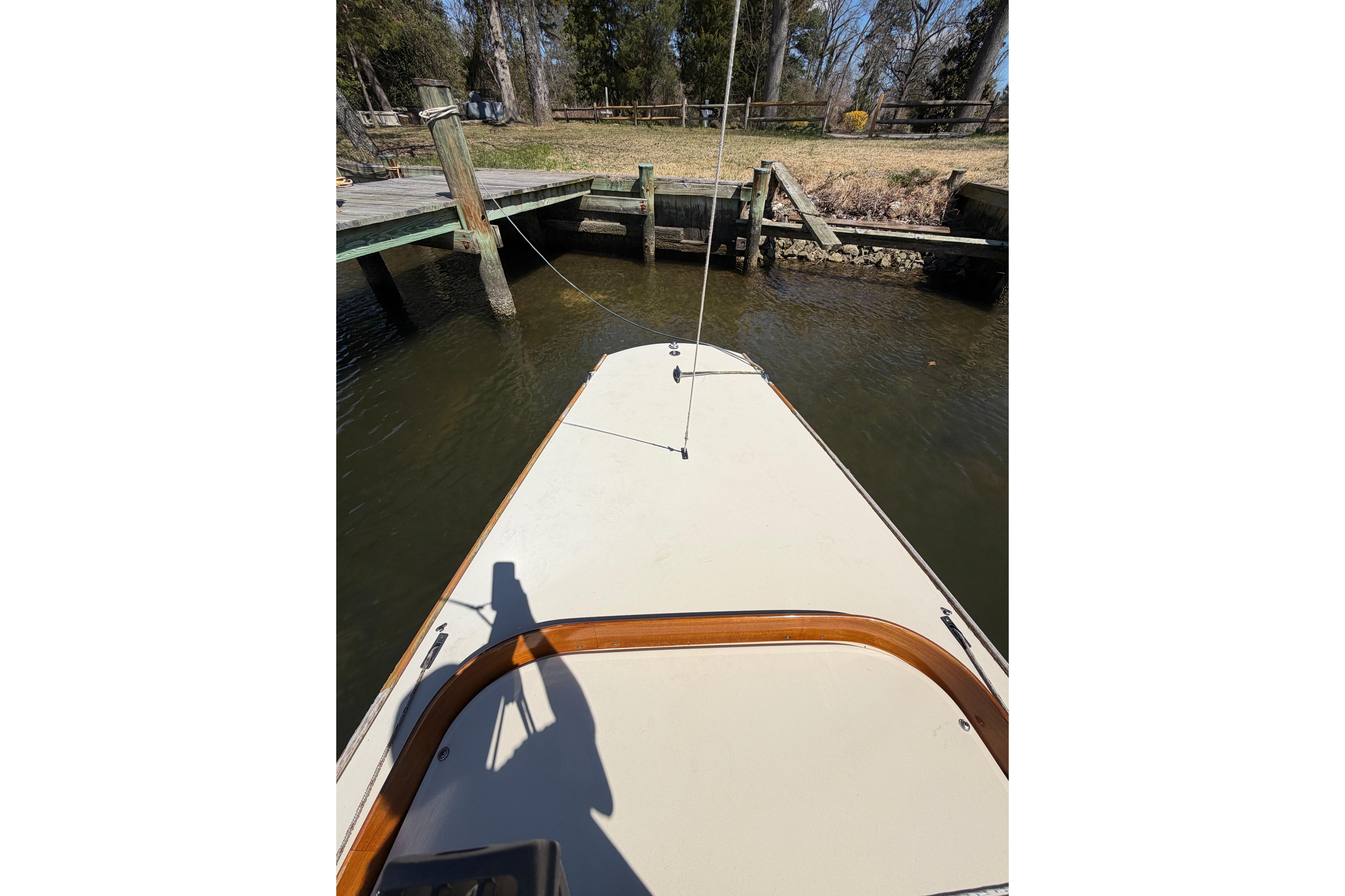 Bow view of 2014 C.W. Hood 32 Daysailer docked by wooden pier.