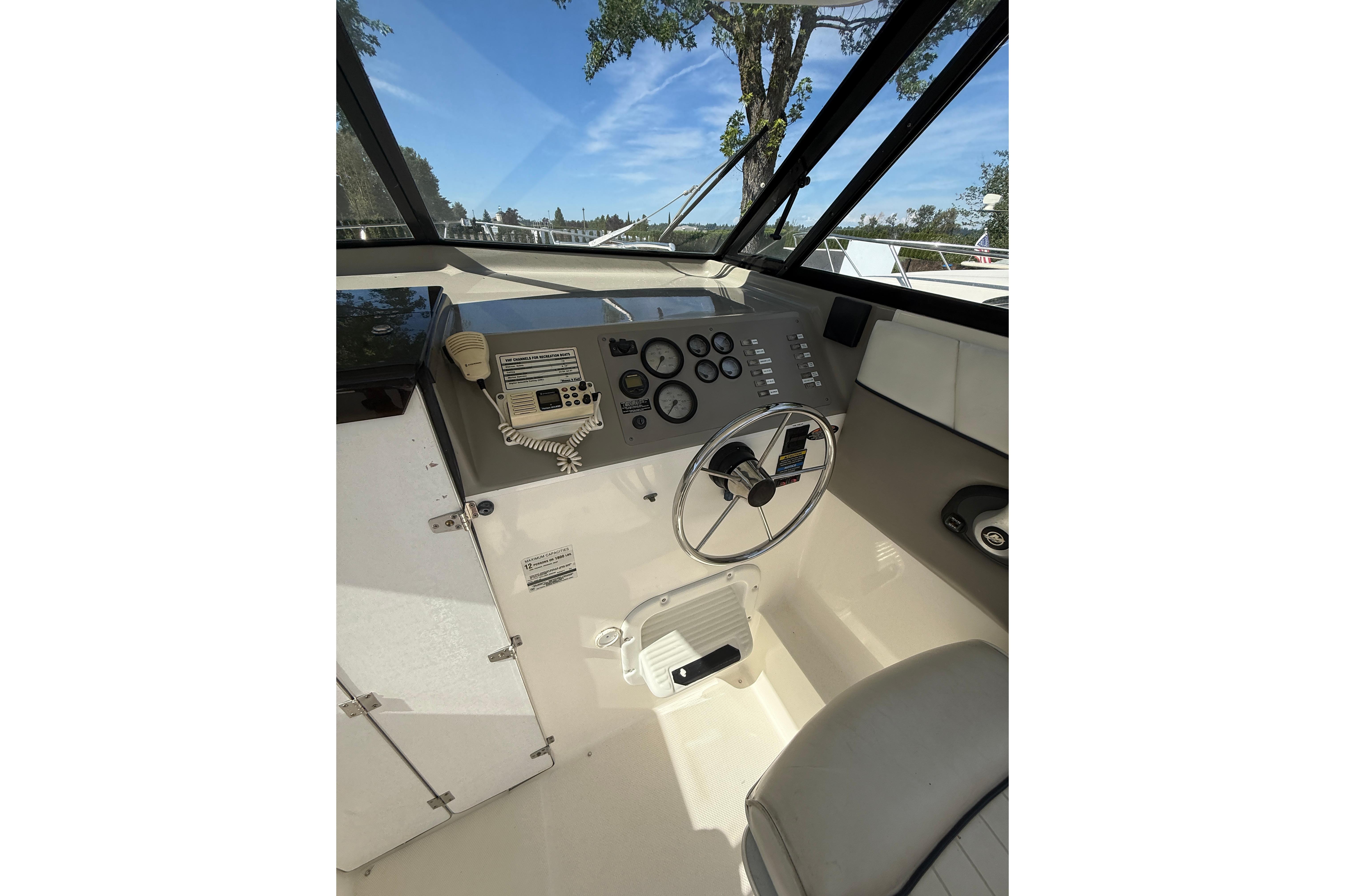 1997 Bayliner 2452 Ciera Express helm with steering wheel and control panel under clear sky.